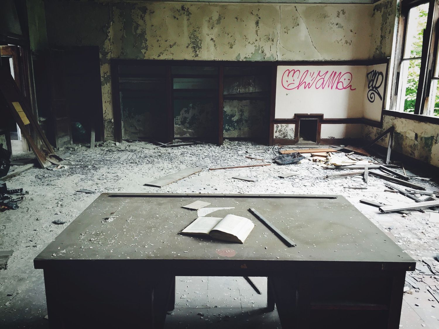 Abandoned interior of a dilapidated school with debris scattered across the floor.