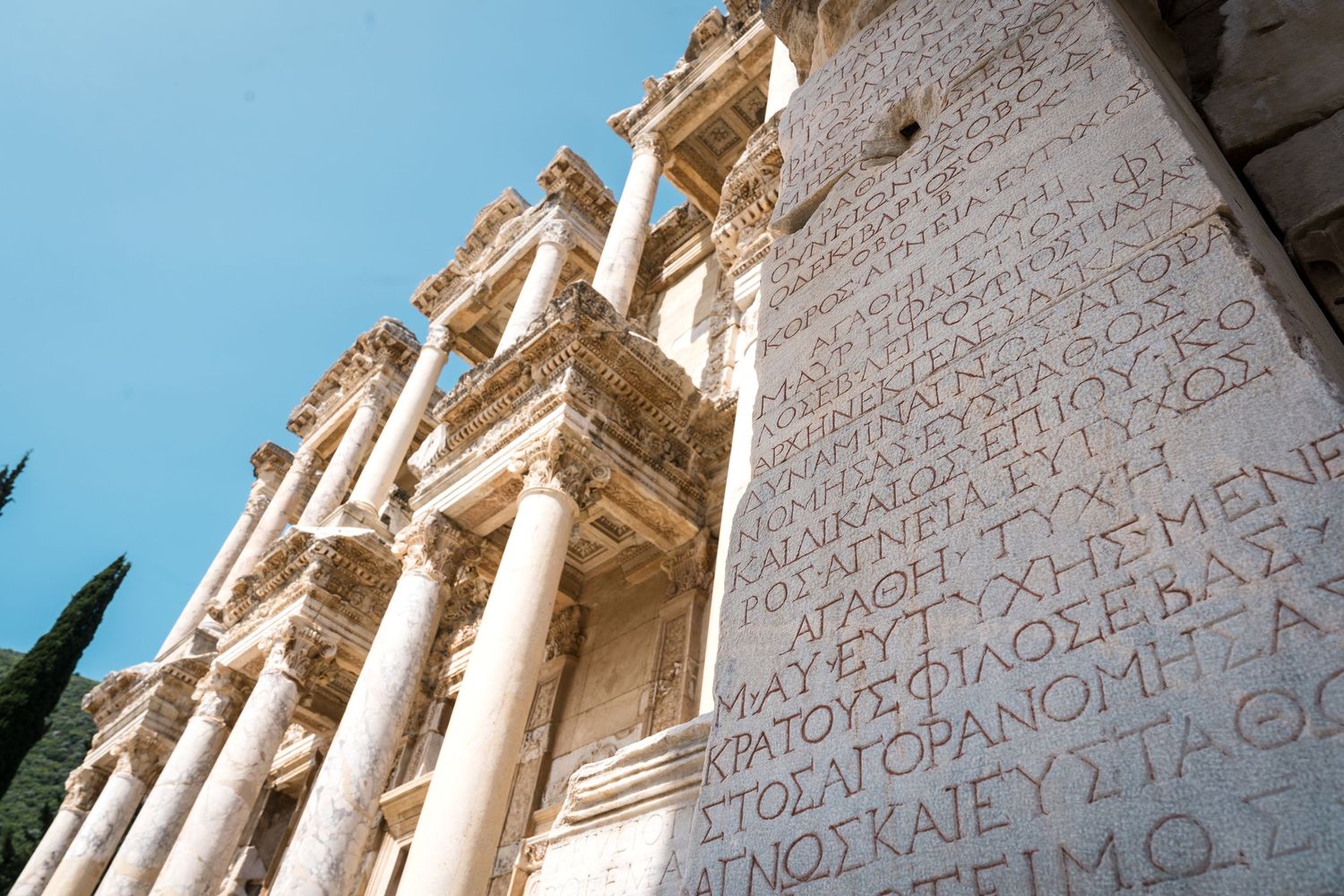 Low angle view of classical Greek architecture with stone columns and inscriptions.