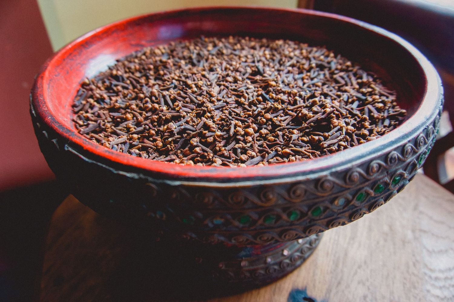 Close-up of whole cloves filling a dark ceramic bowl.