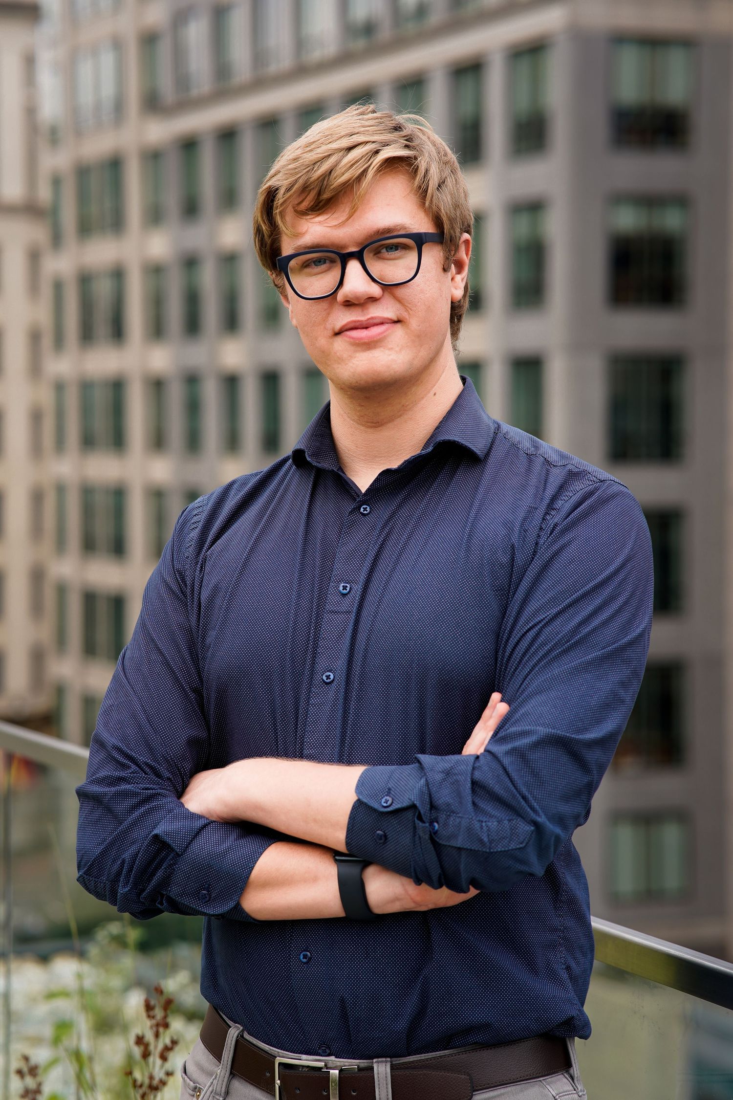 Business portrait series showing relaxed poses in navy shirt against modern architecture.