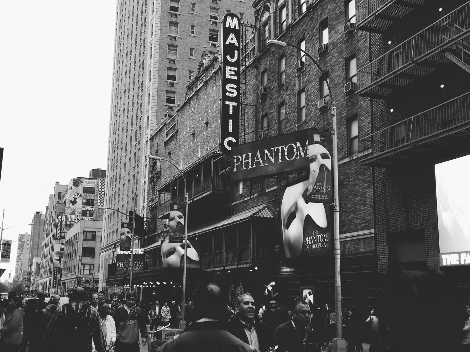 Black and white street scene showing the Phantom theater marquee in an urban setting.