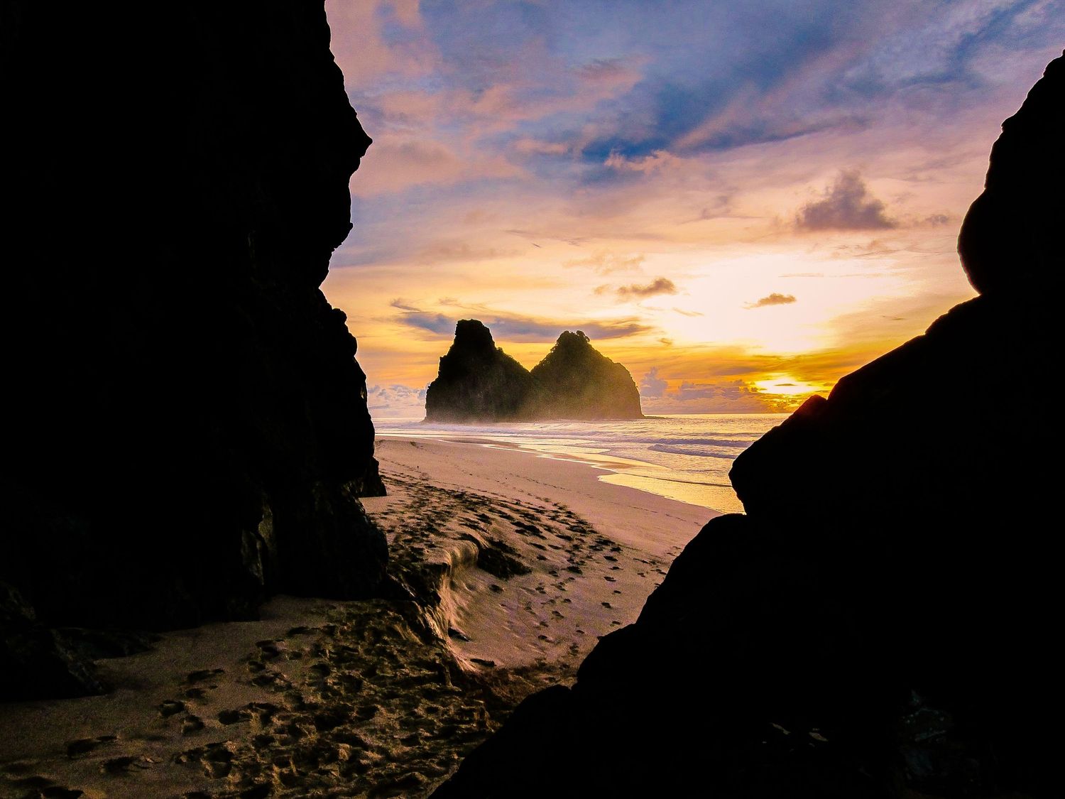 Coastal cave openings frame dramatic sunset views over the Atlantic Ocean.