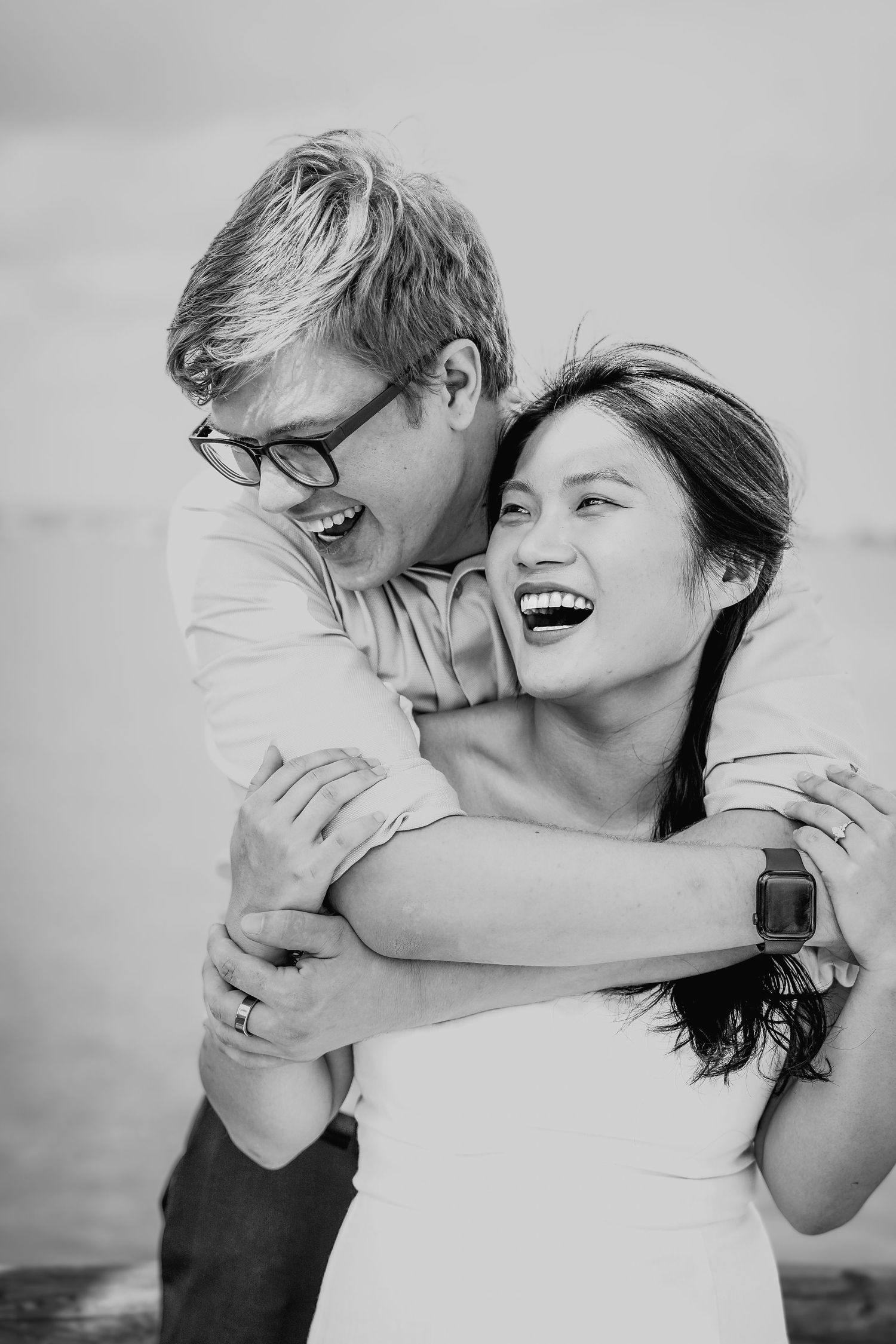 Black and white candid photos capturing joyful laughter and embraces between a couple.