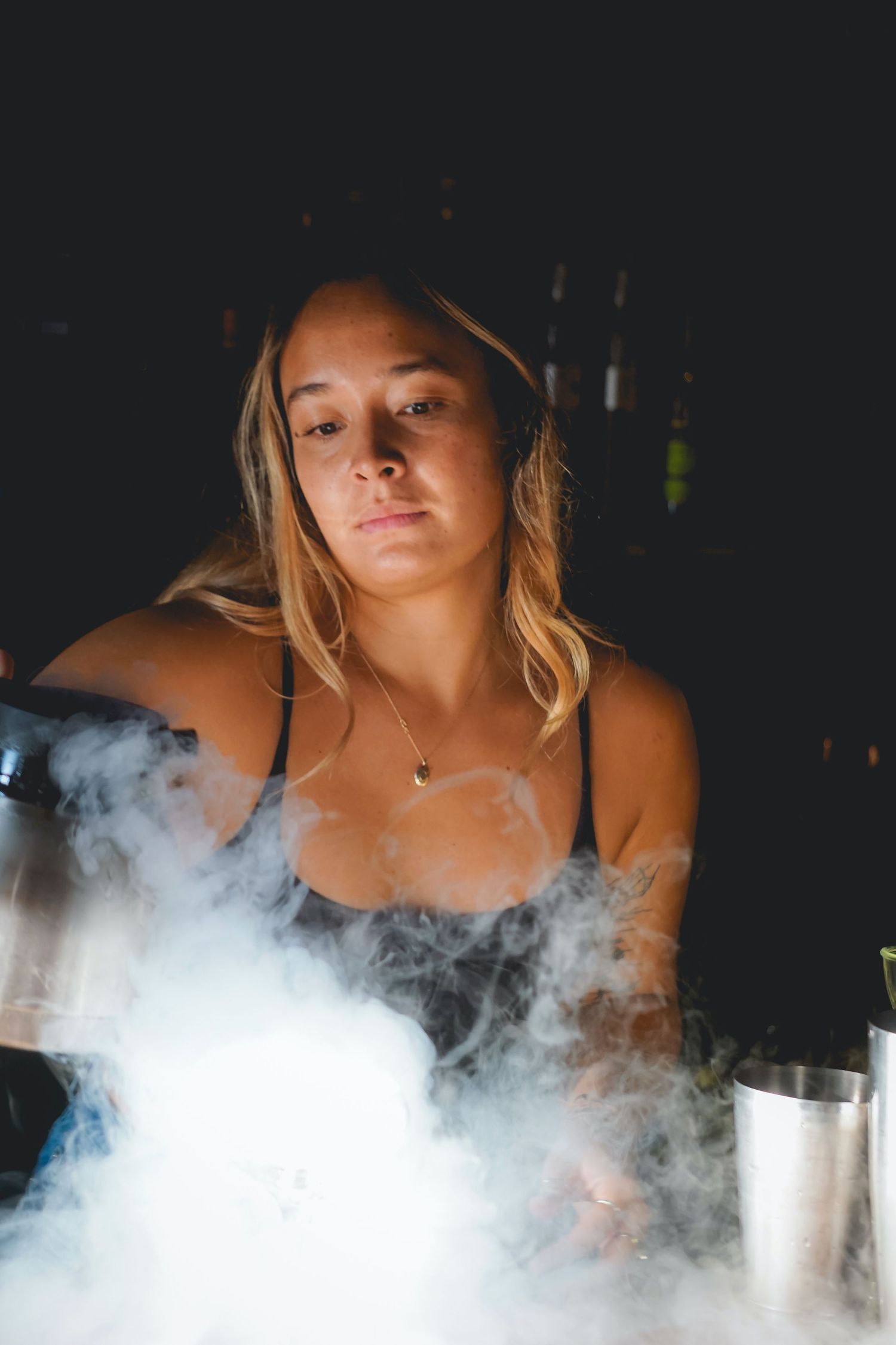 Bartender surrounded by dramatic smoke effects in dark moody lighting.