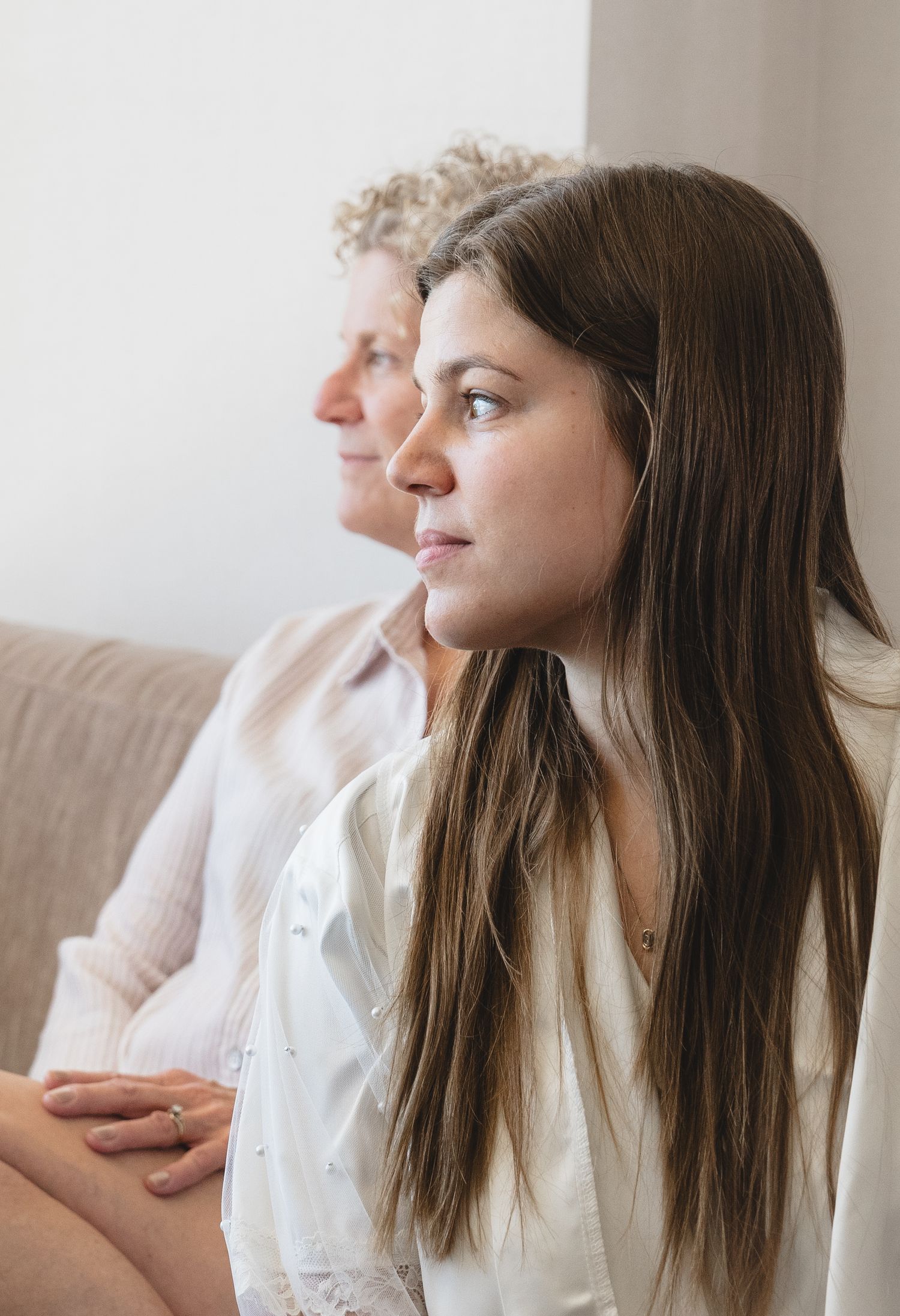 Two people sit together on a couch in contemplative profile.