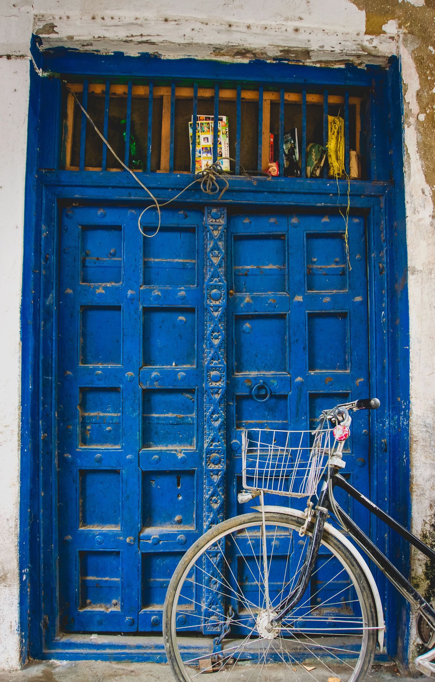 Vintage bicycle parked against bright blue traditional doors with ornate metalwork details.