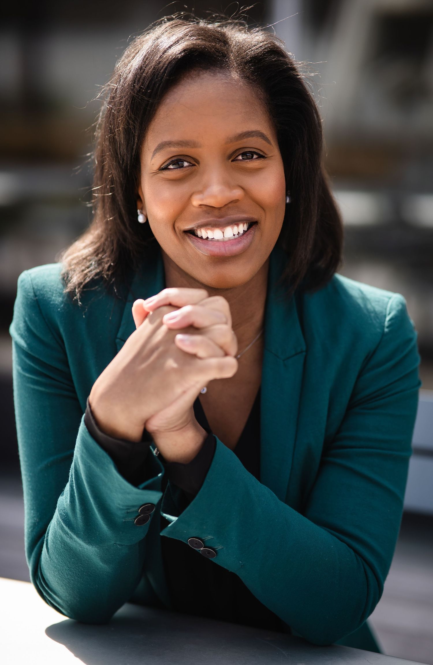Professional headshots showing joyful expressions while wearing a dark teal blazer.