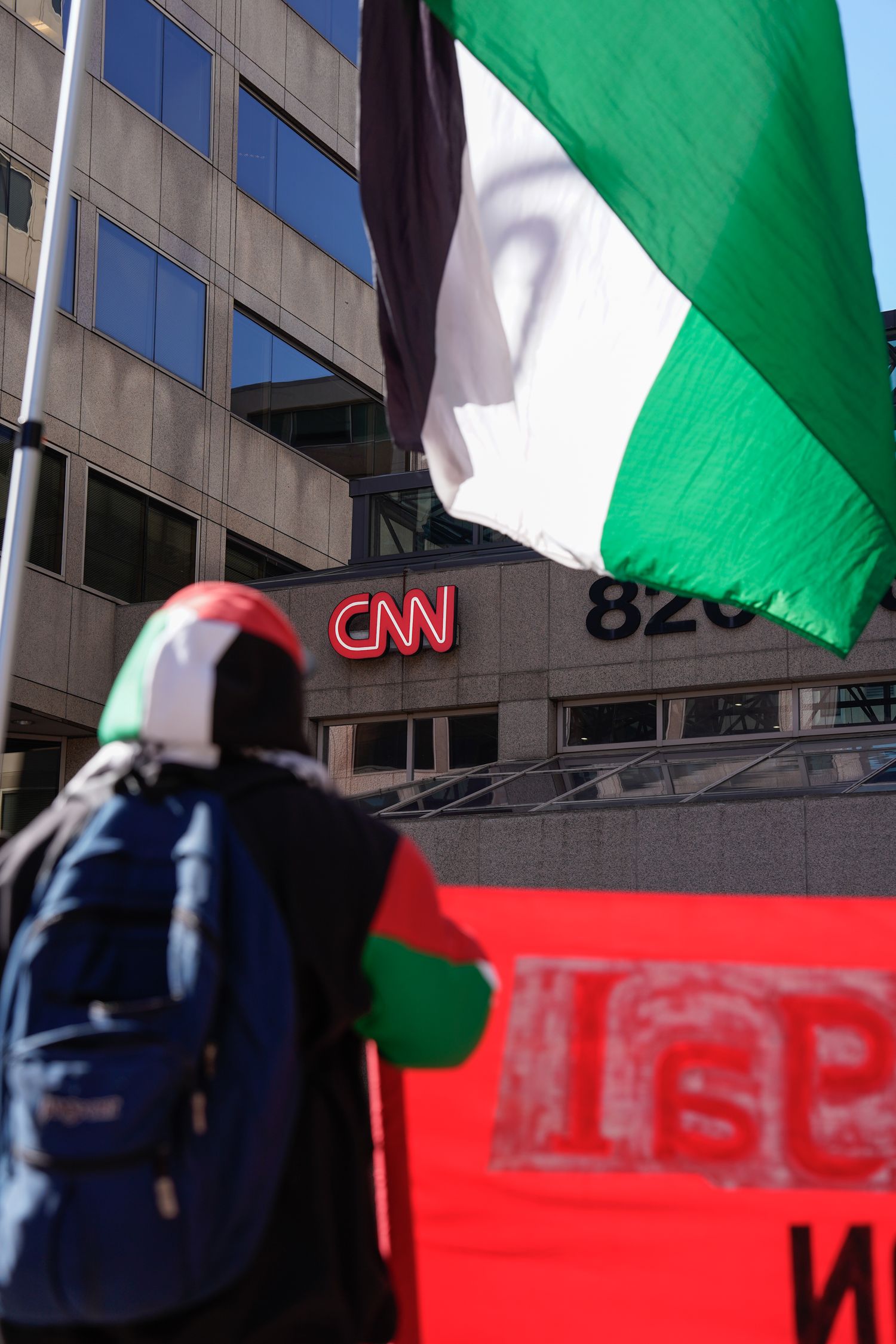 Palestinian flags waving in front of CNN building during protest.