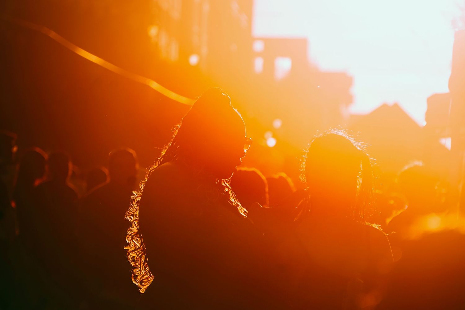 Silhouettes of crowd against dramatic orange sunset sky.