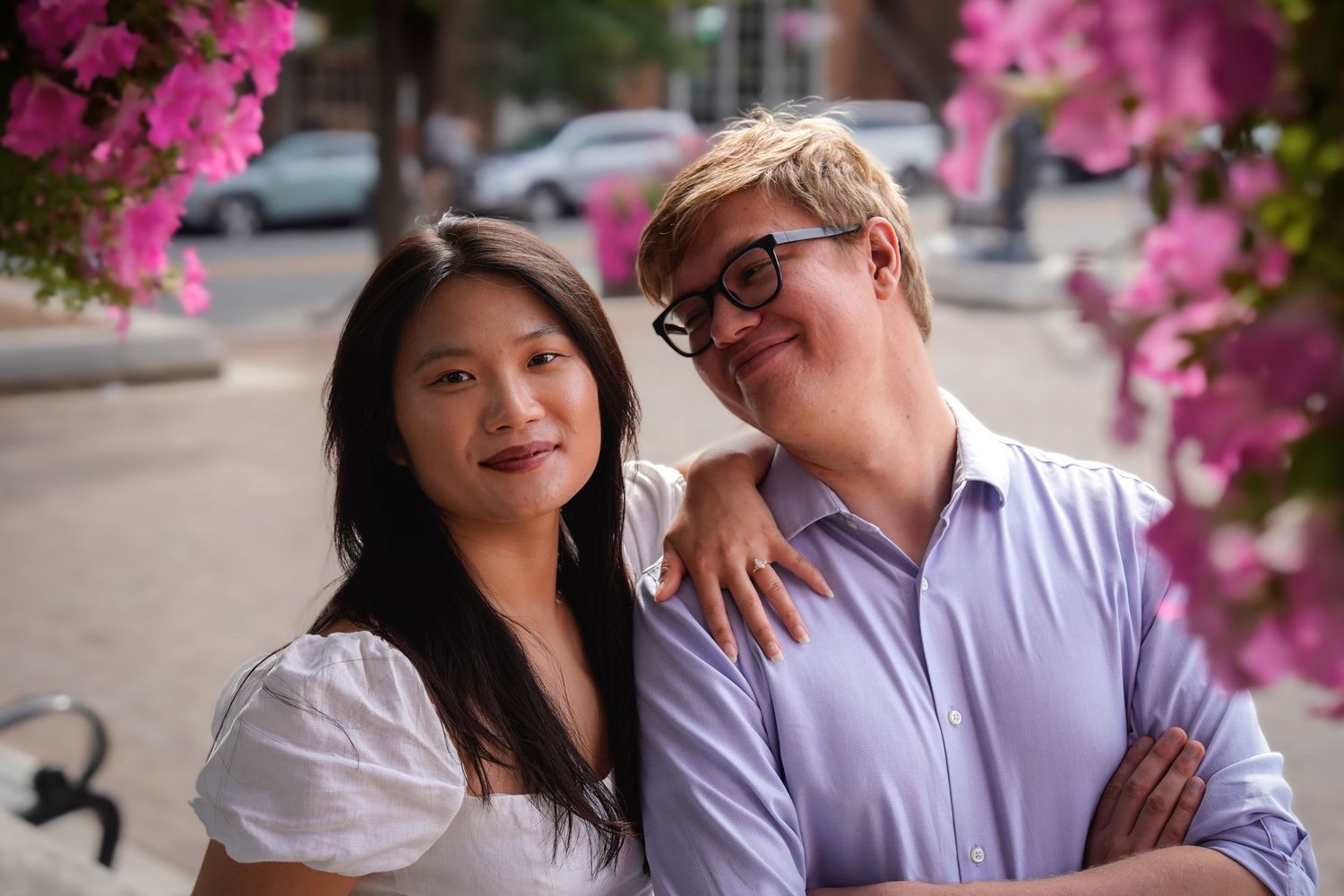 Romantic couple sharing intimate moments under blooming pink cherry blossoms in a park setting.