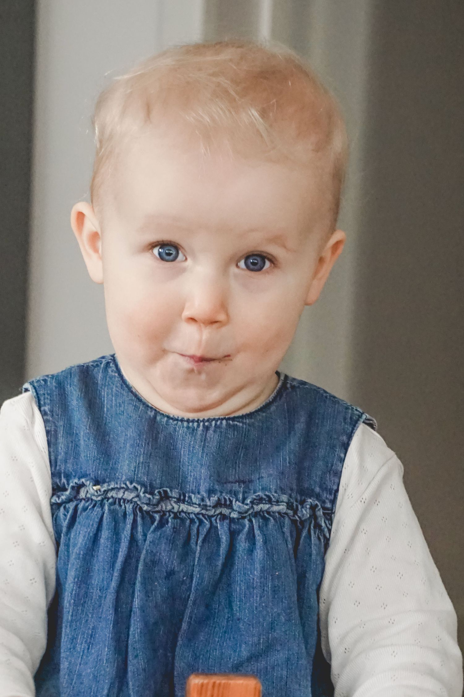 Baby wearing denim dress and white shirt making cute expressions.