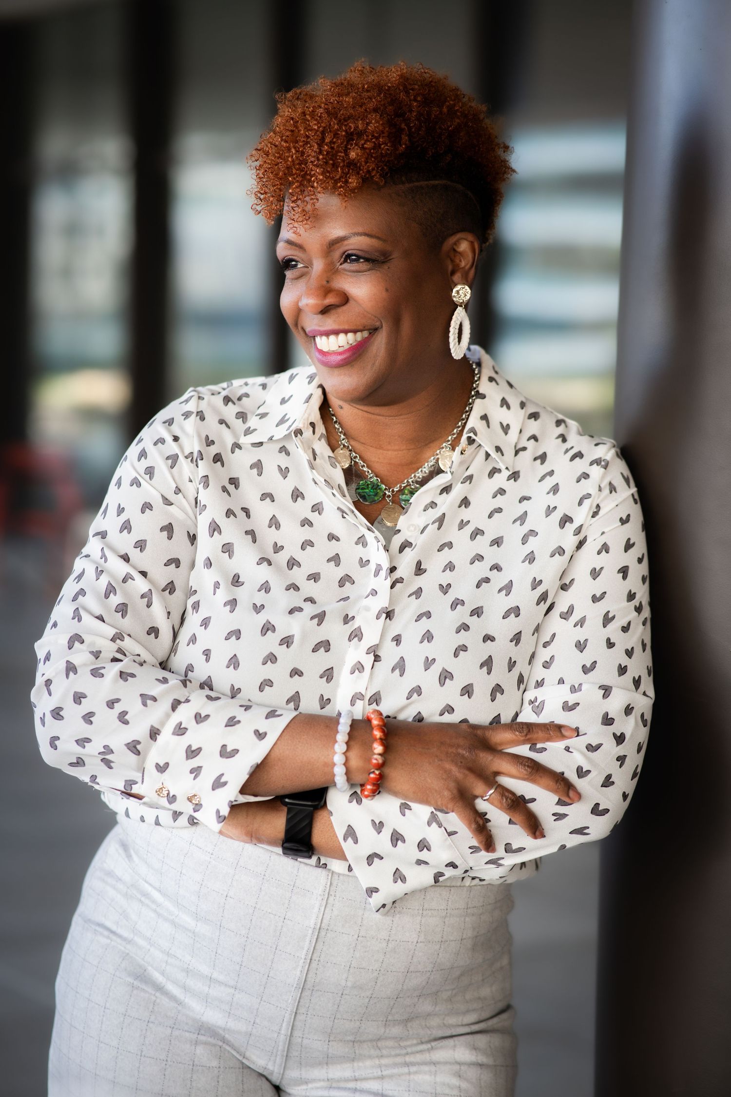 Professional photos of someone wearing a white patterned top and light colored pants in an office setting.