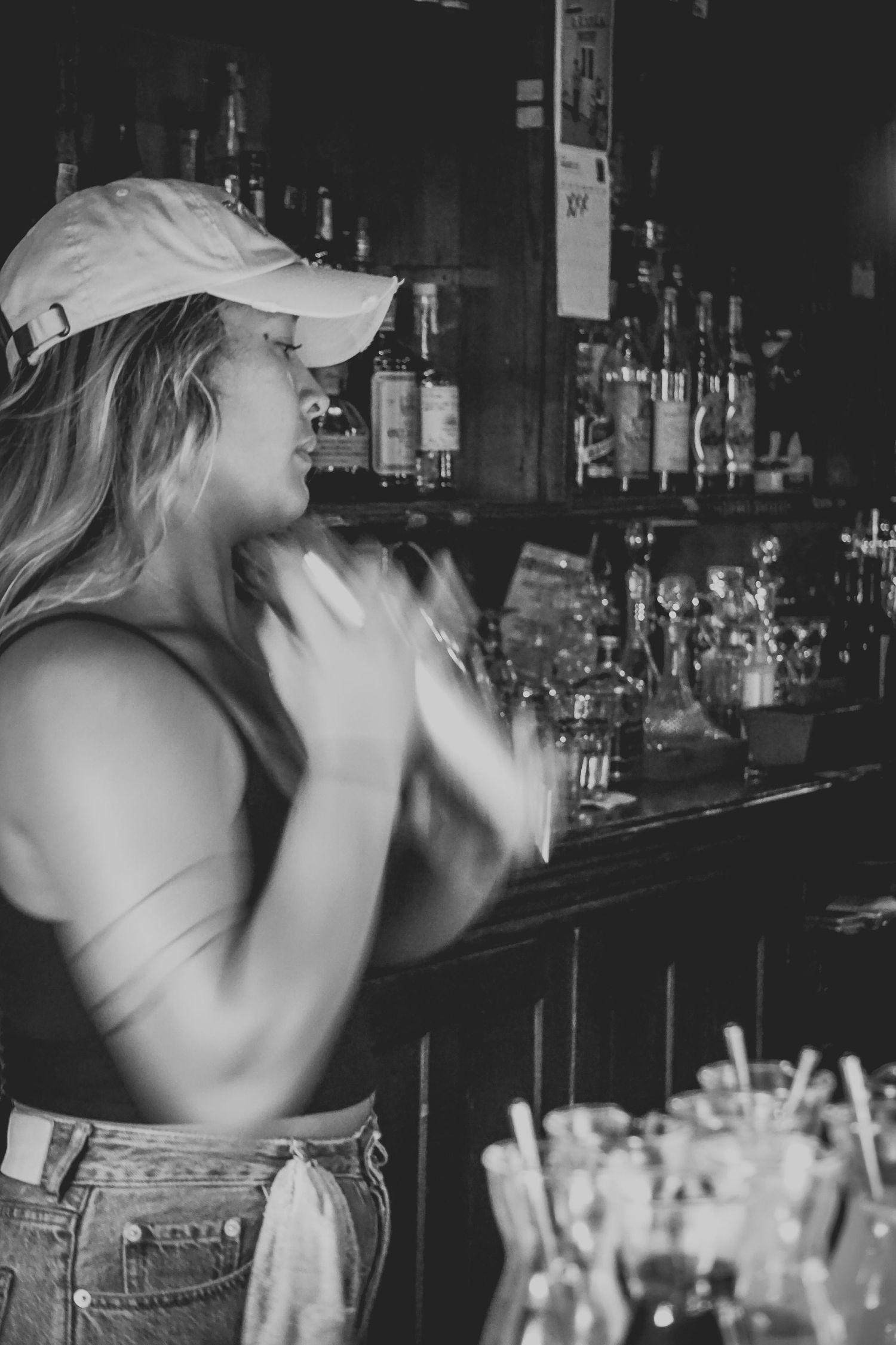 Energetic bartender in casual attire working behind bar counter.