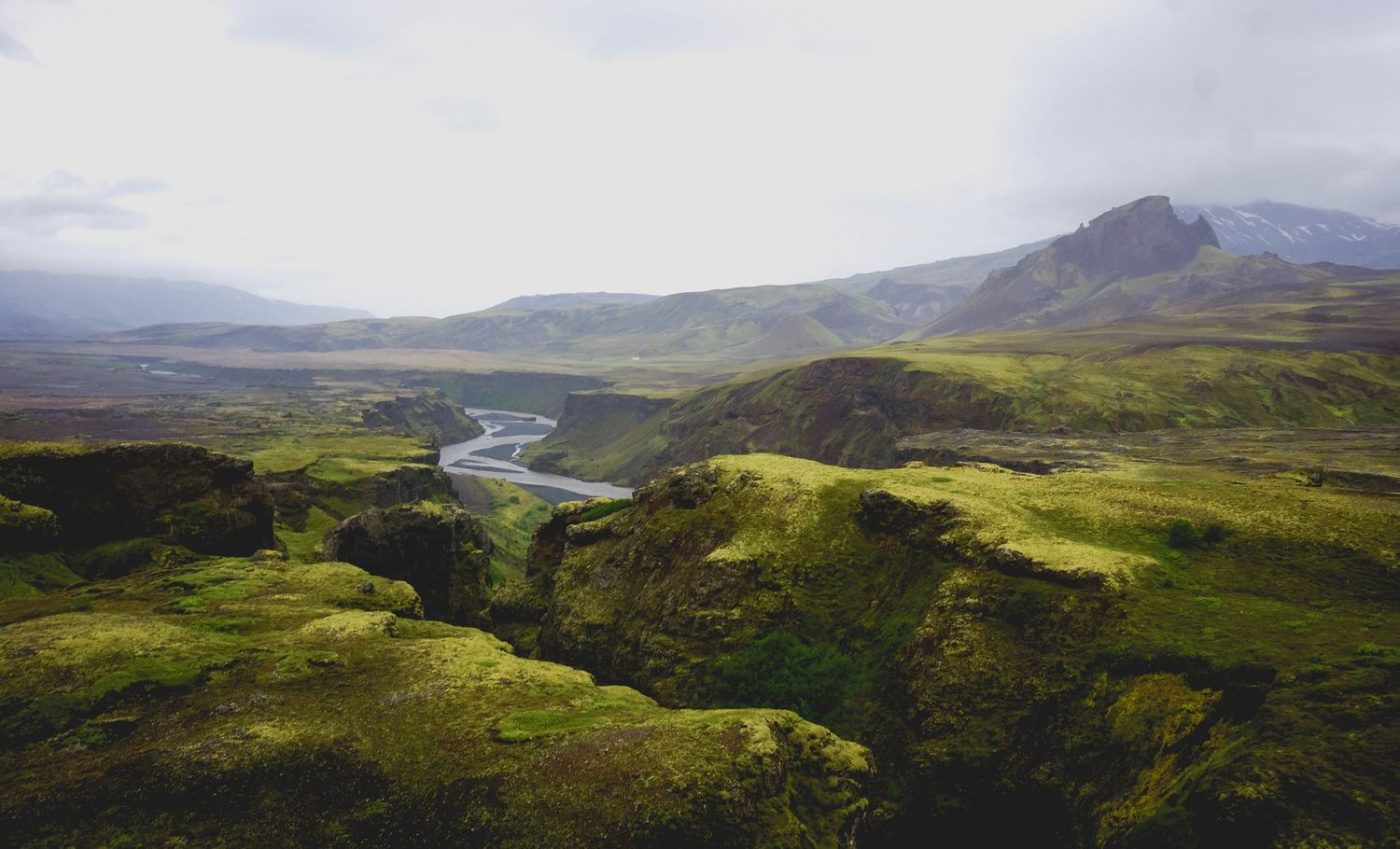 Rolling green hills and mountains stretch across a dramatic landscape with winding rivers and valleys.
