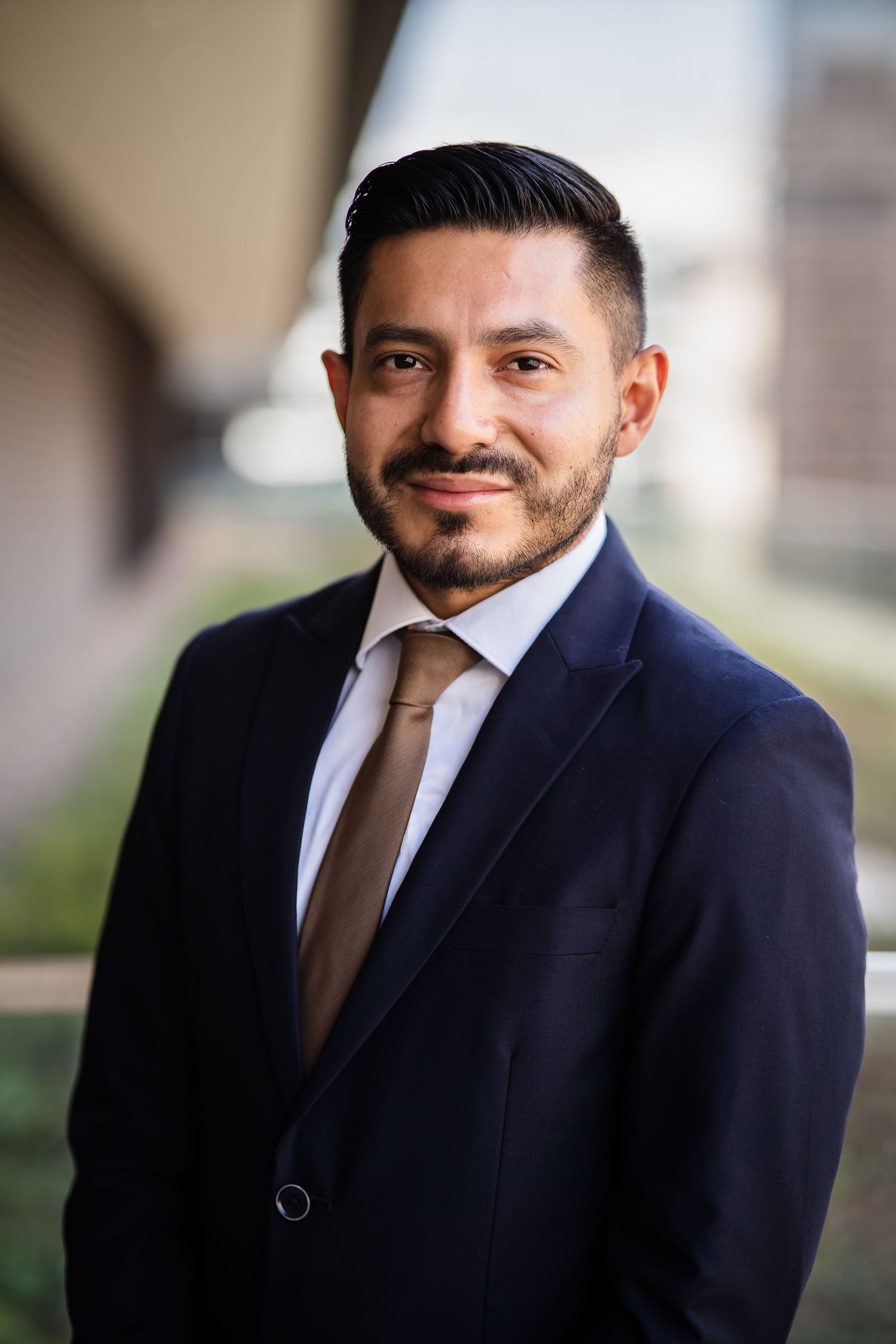 Business professional in dark suit and tie photographed against neutral background.