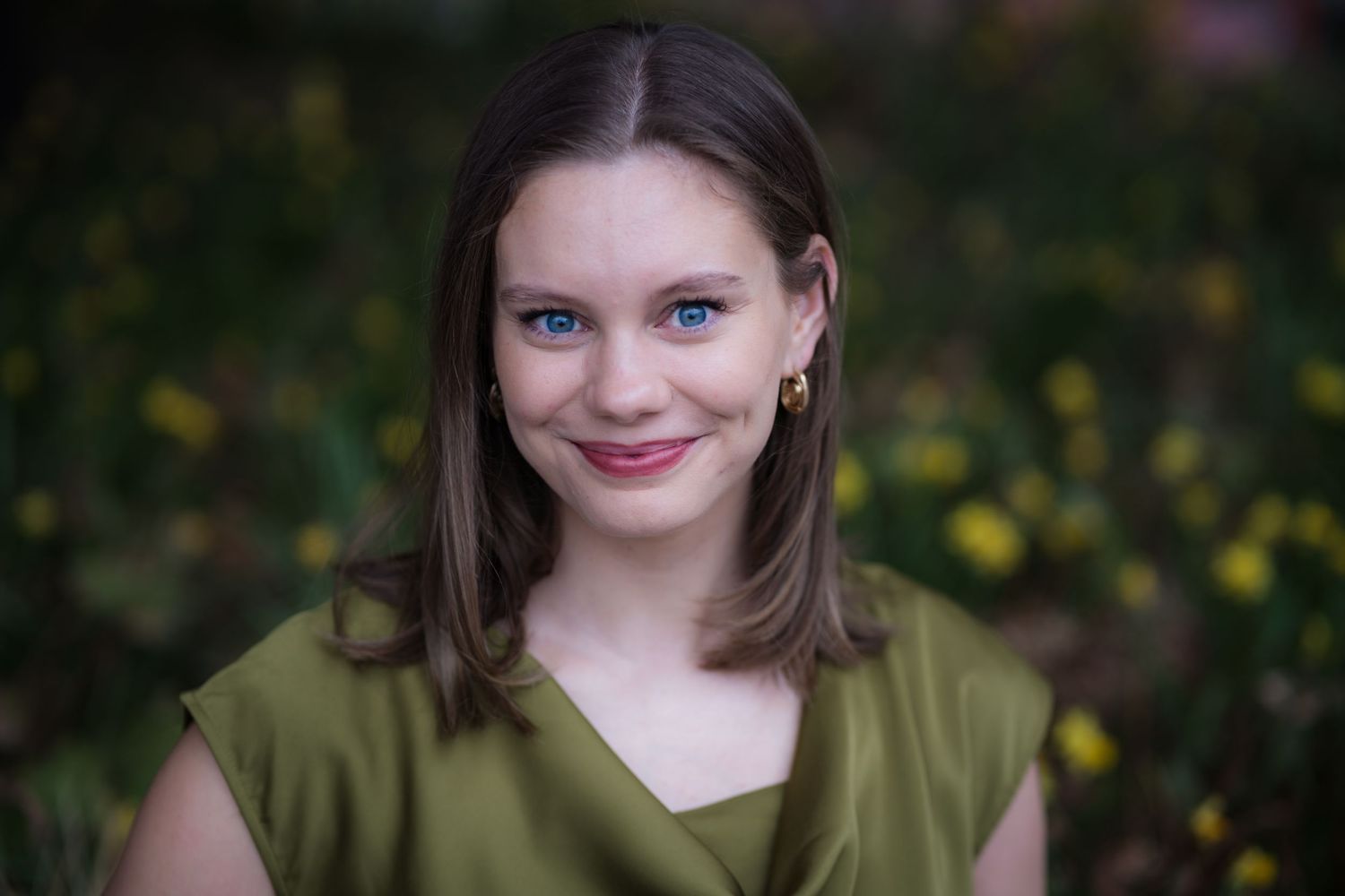 Outdoor portrait with yellow flowers in background and olive green top.