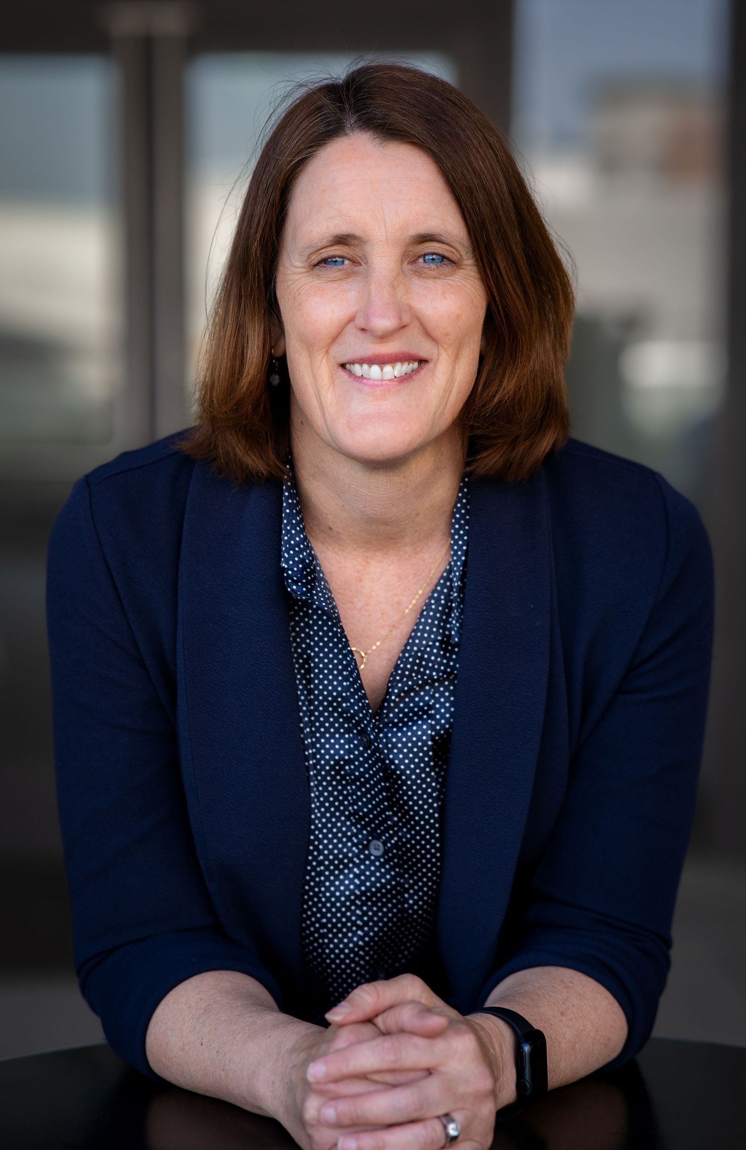 Professional headshots showing a person in a navy blazer and polka dot blouse against a blurred background.