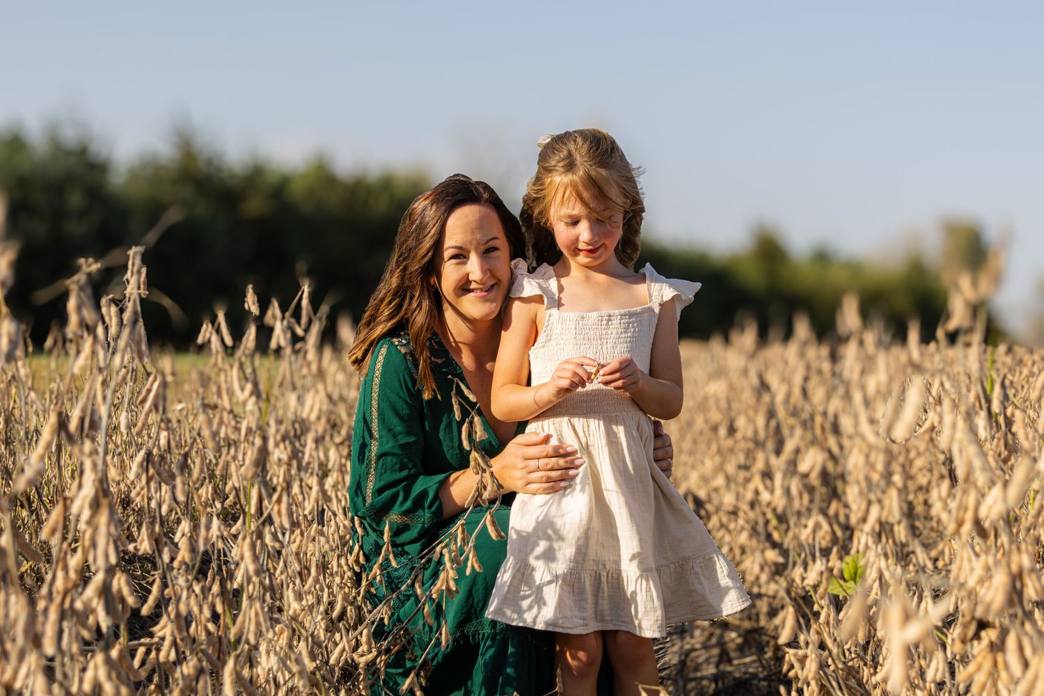 Mother and daughter sharing a playful moment among a field of beans.