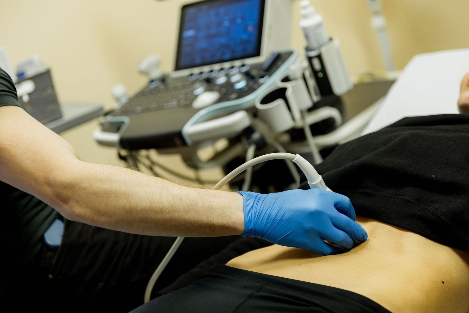 Medical professional performing an ultrasound examination on a patient's abdomen using a handheld probe.