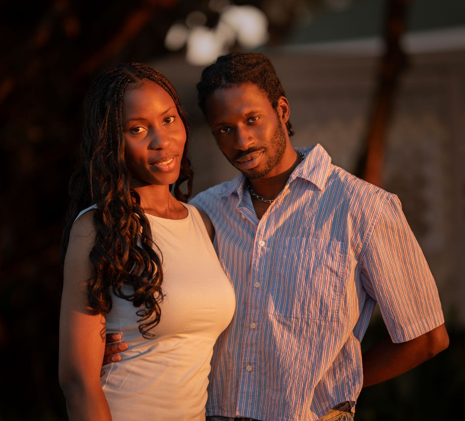 Smiling couple posing together outdoors in warm evening light.