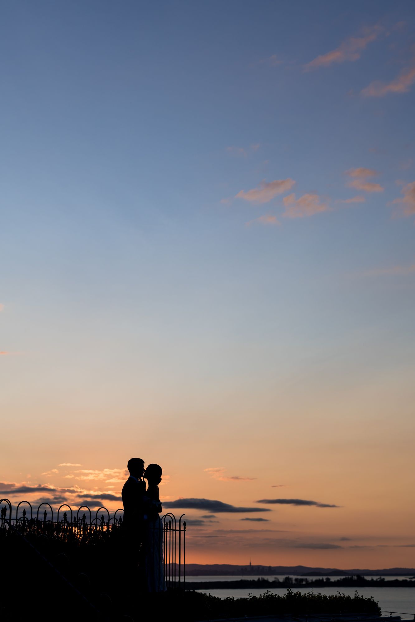 a sunset image of a dark blue and orange sky with a silhouette of a bride and groom embracing at Mudbrick