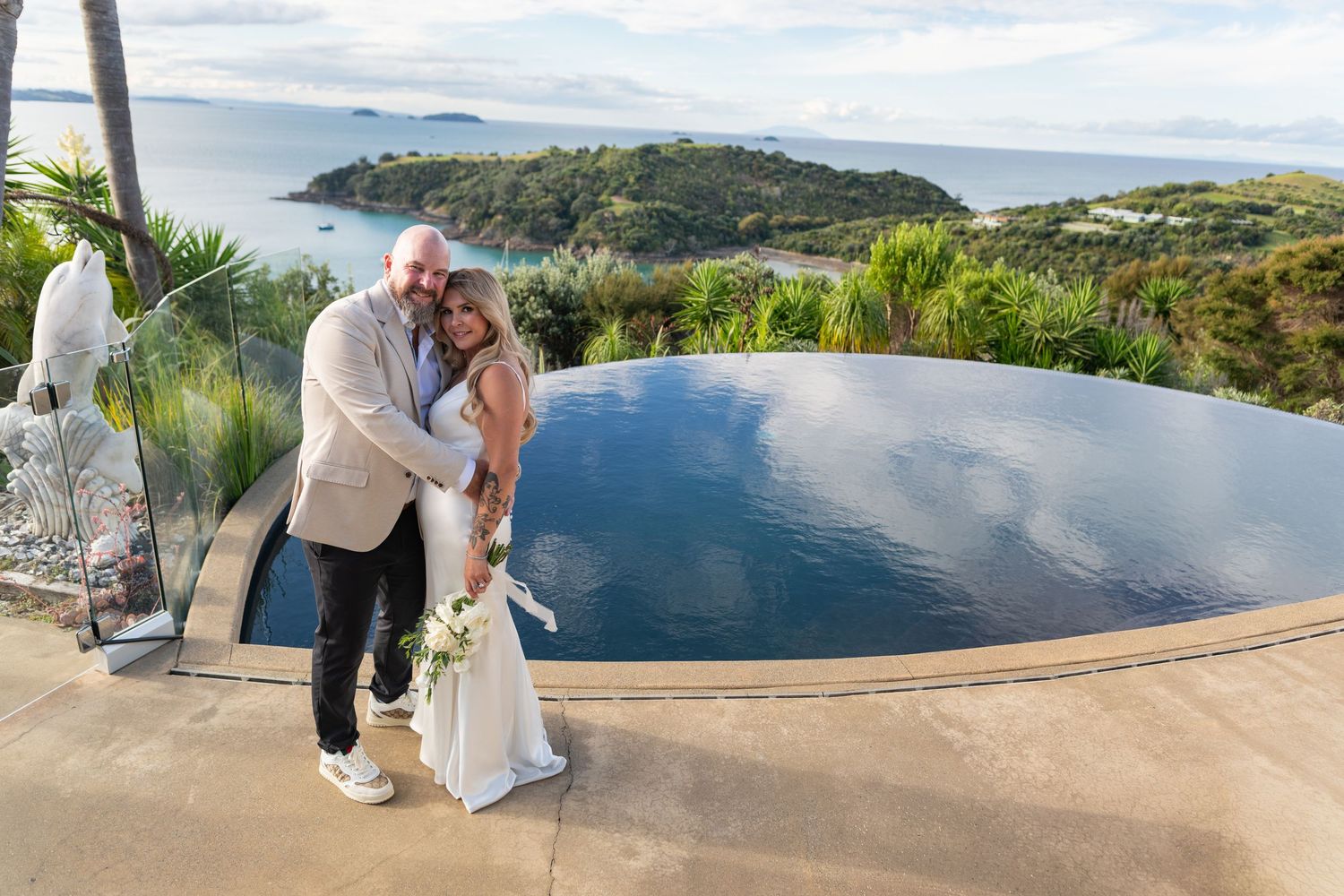 a wedding couple stand in front of the infinaty pool at Delamore Lodge on Waiheke