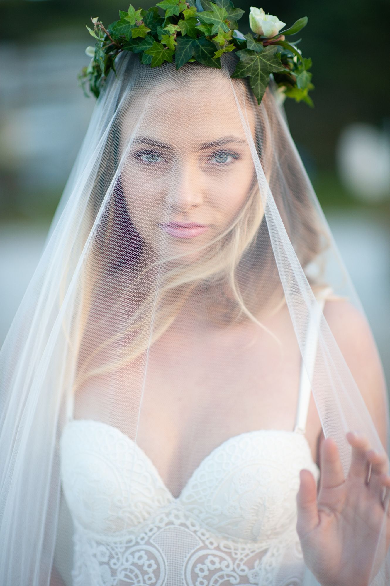 a beautiful bride looks straight at the camera underneath a fine vale covering her face