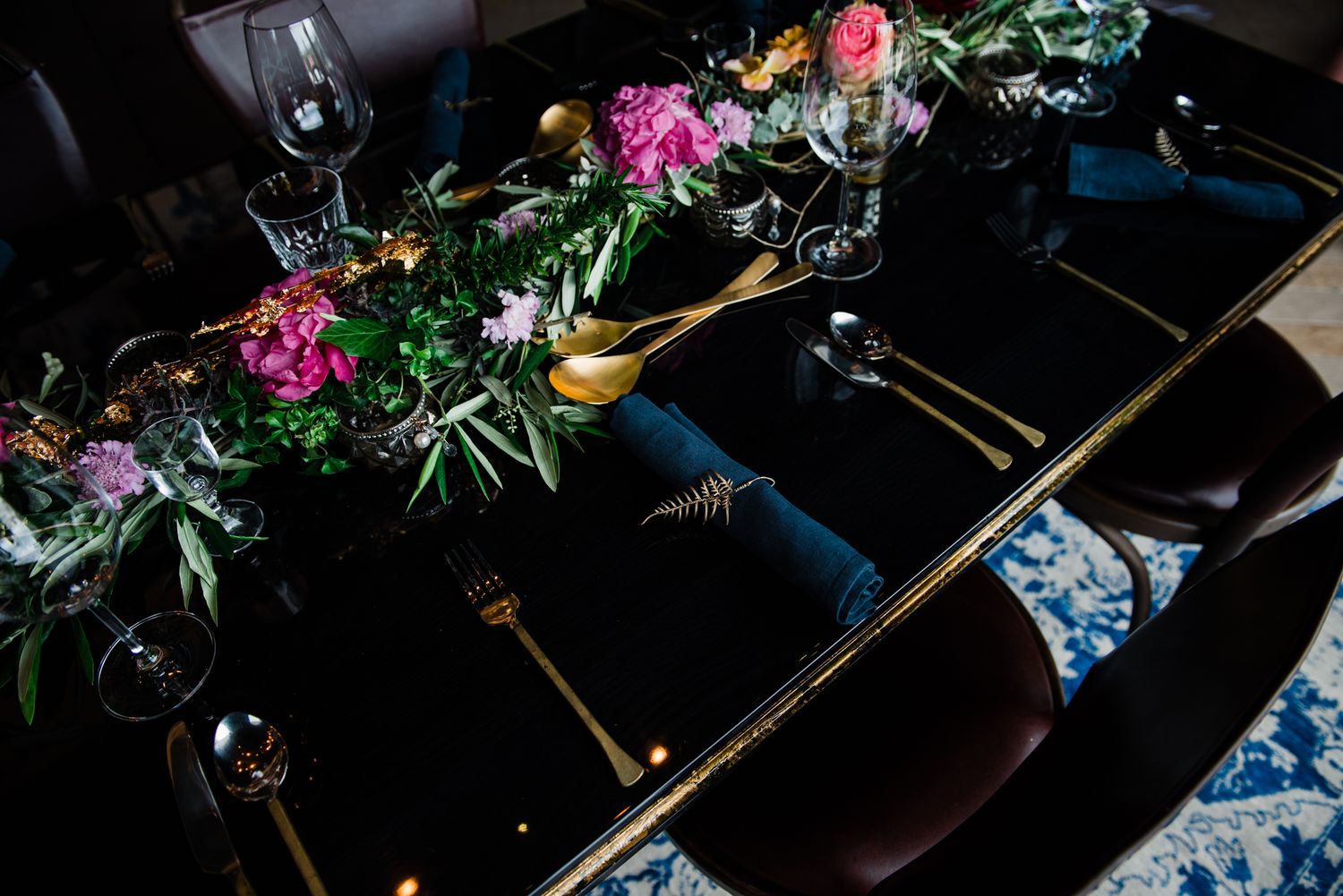 an ornate place setting of gold cutlery and pops of bright coloured blooms on a dark sultry background at Tantalus Estate