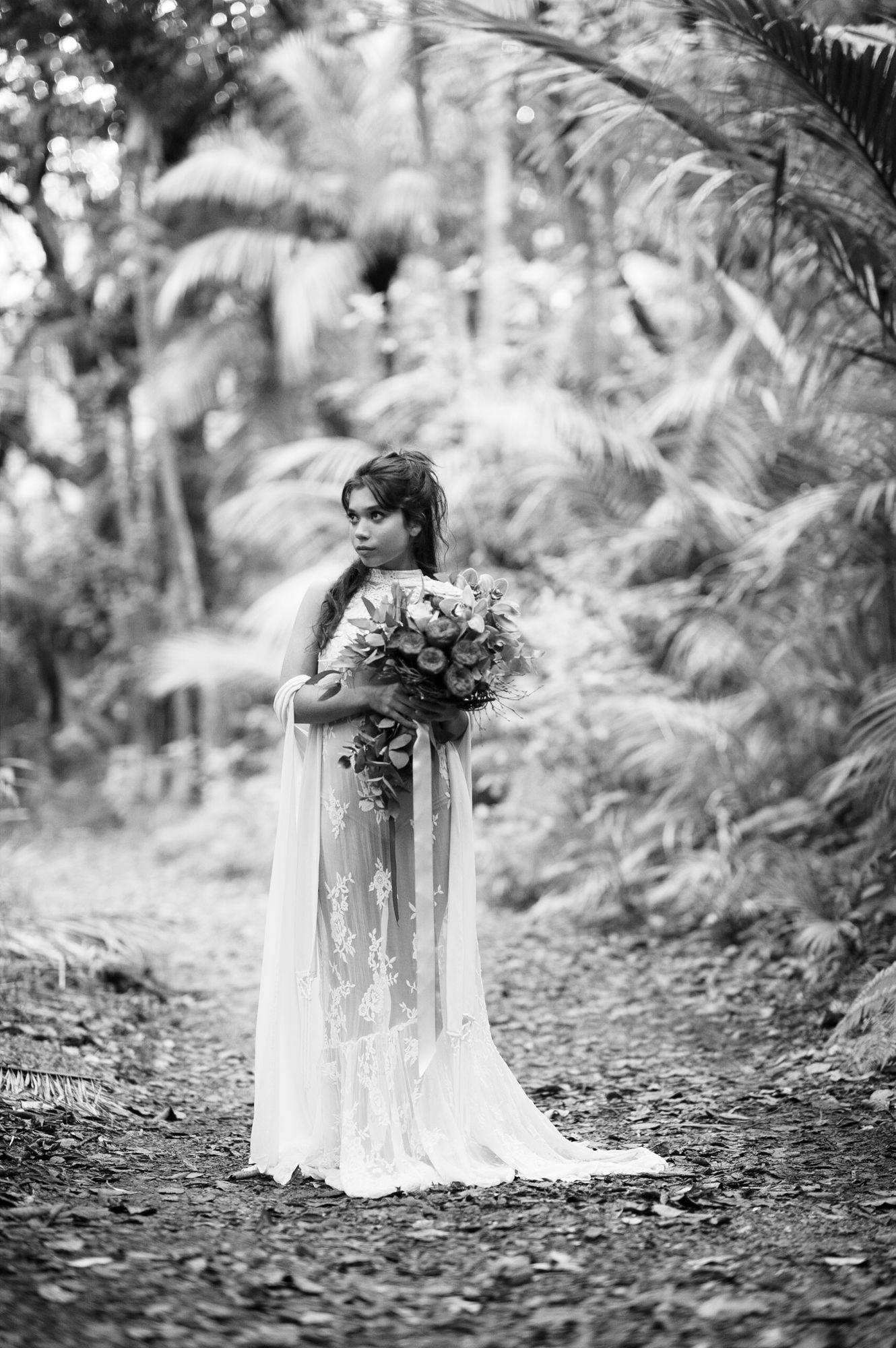 a black and white image of a beautiful bride with the New Zealand native bush framing her