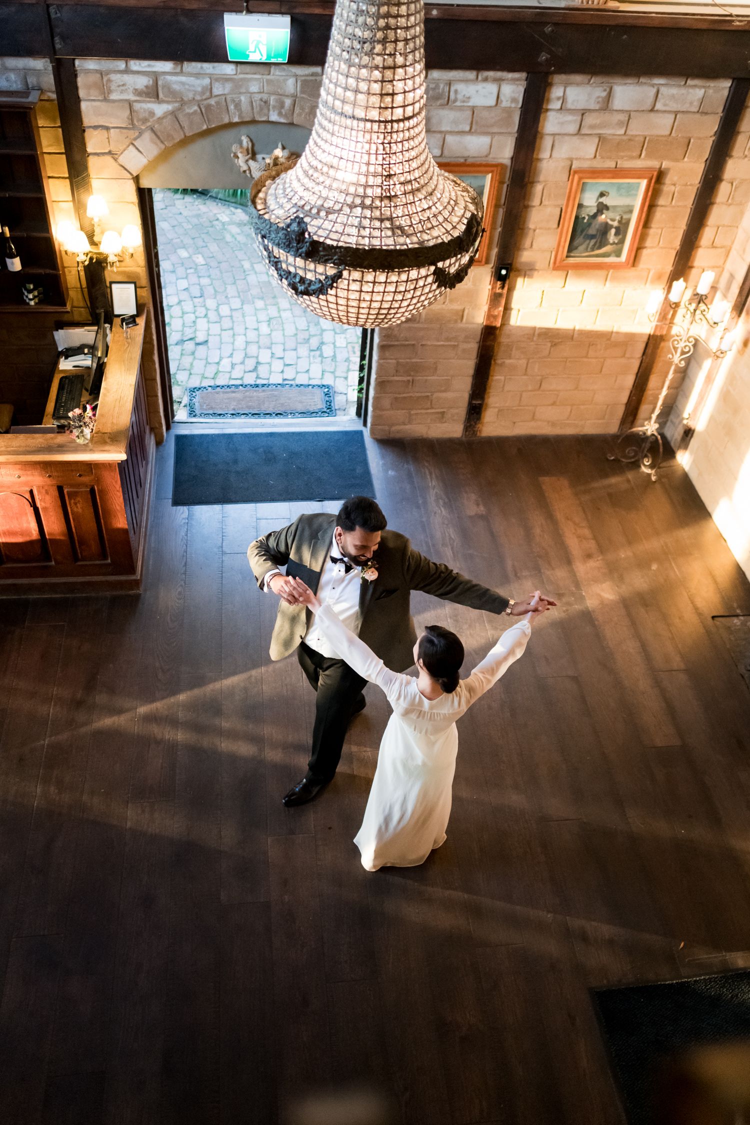 A wedding couple dance low down from the balcony at Mudbrick vineyard underneath the chandelier
