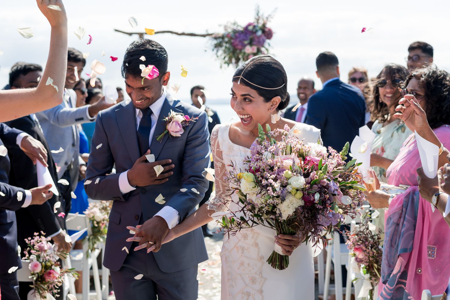 Confetti pours over a bride and groom whilst they walk down the aisle with happiness