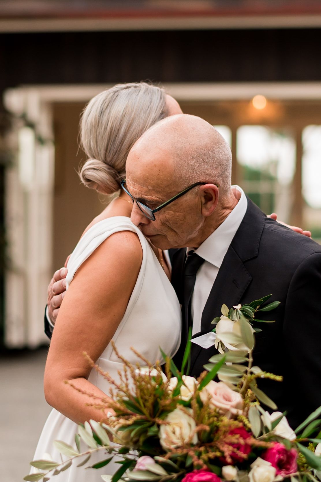 a father embraces his daughter one last time as he hands her over at the end of the isle to get married