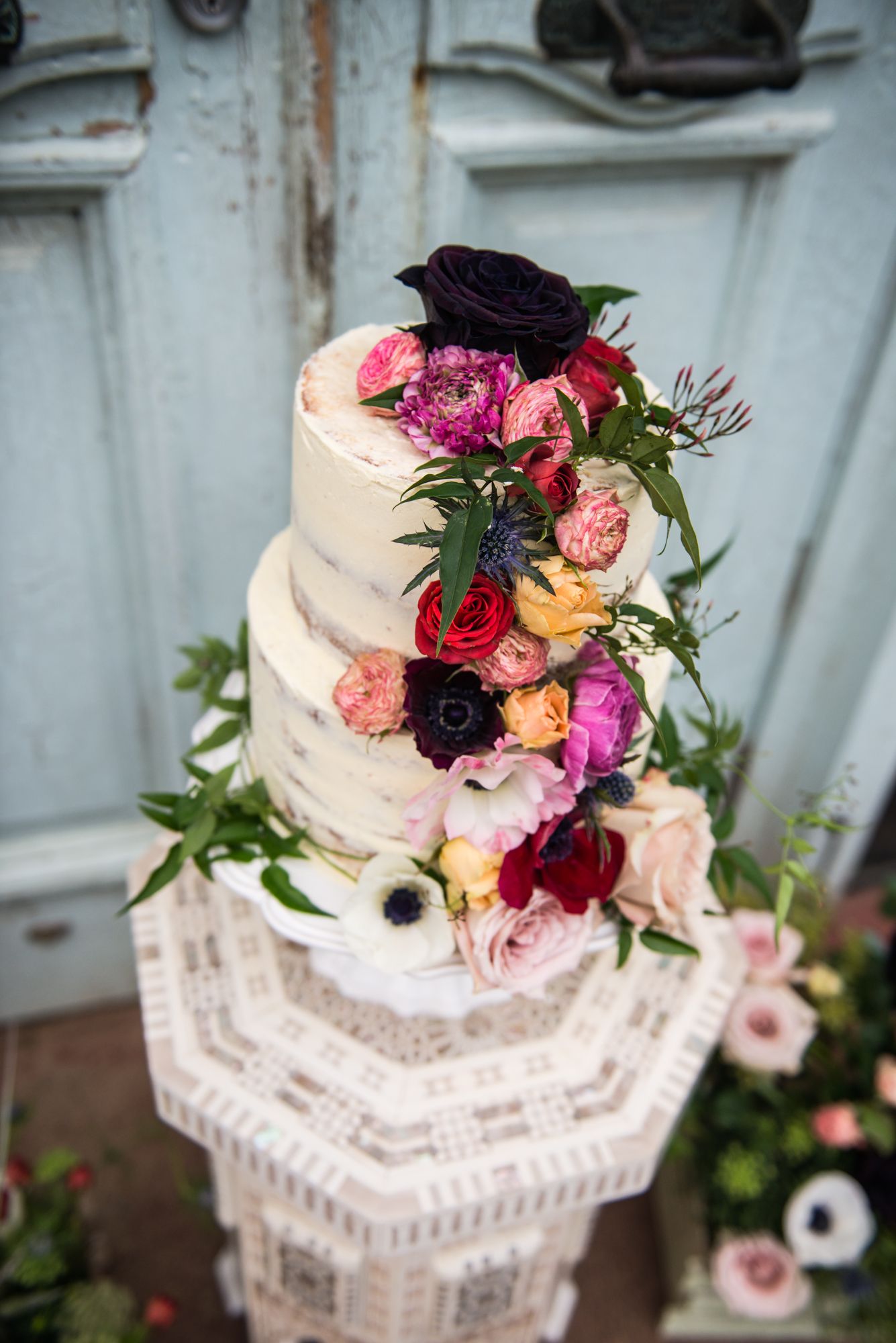 a stunning wedding cake with beautiful flowers cascading down three tiers on an ornate stand