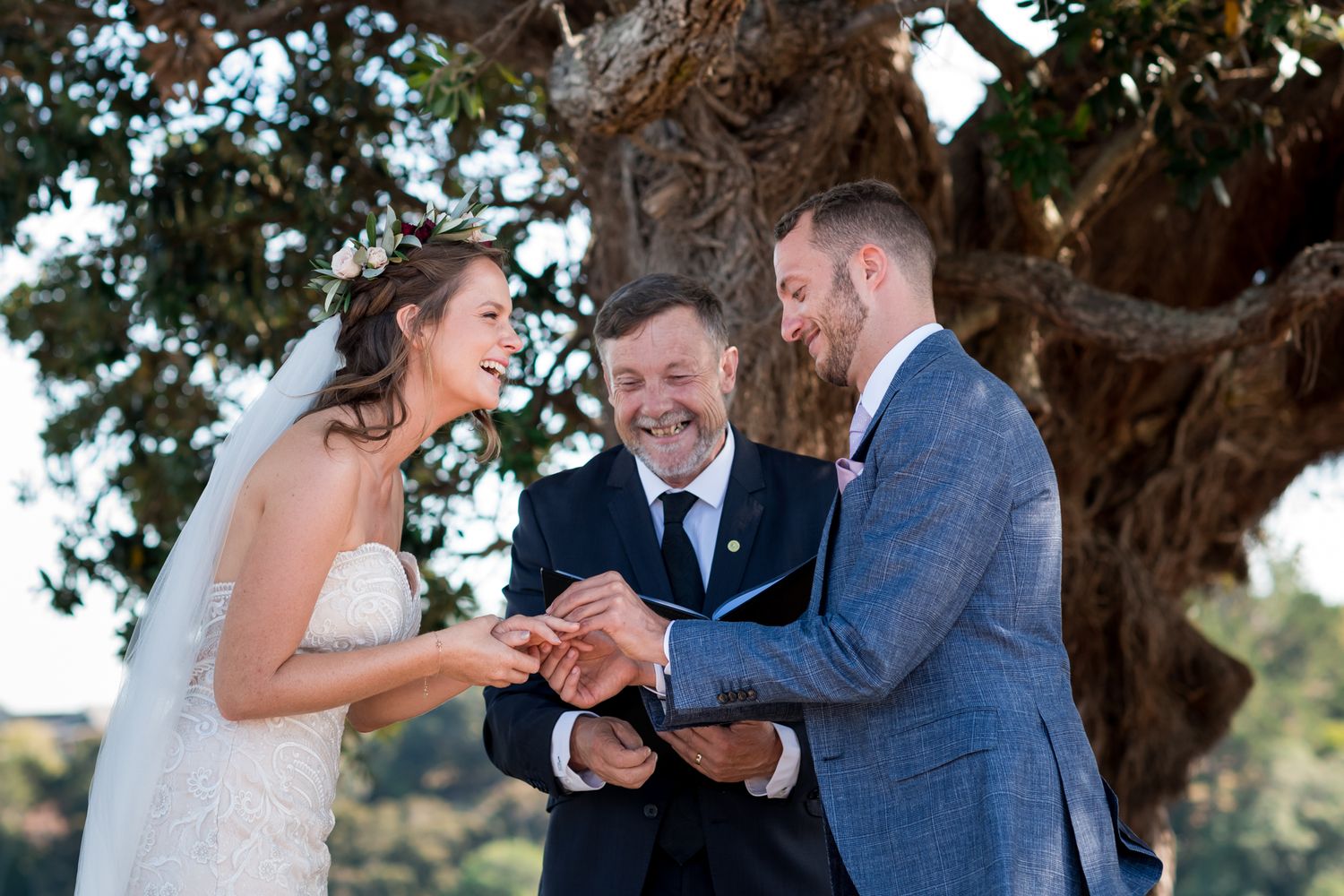 A bride and groom laugh with each other whilst putting on the ring during the ceremony