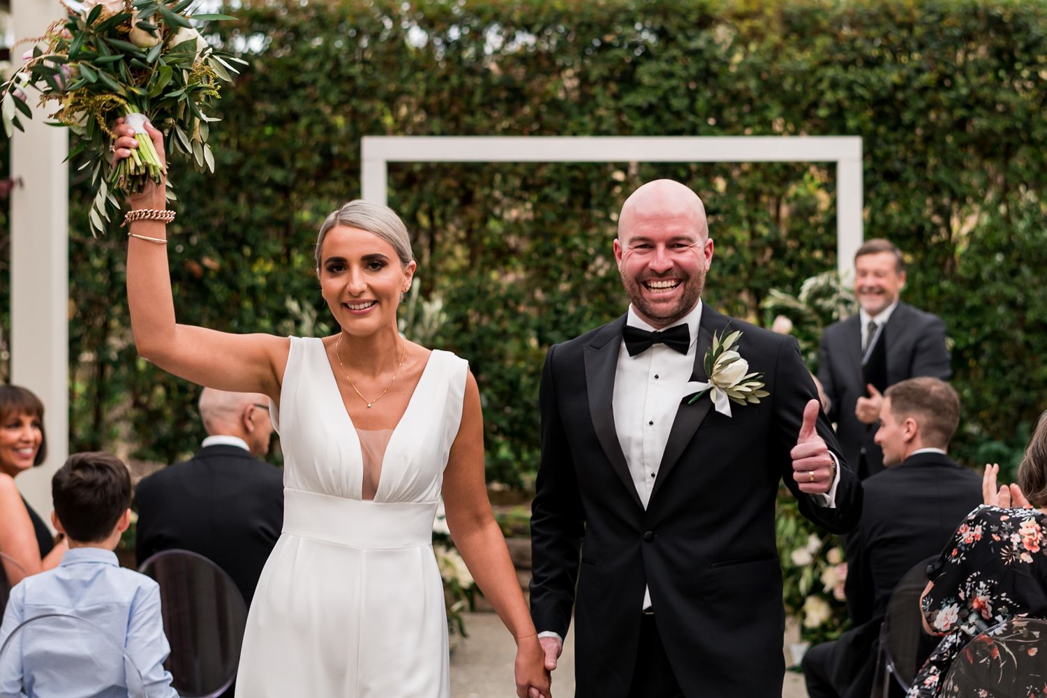 a close up of a bride and groom walking towards the camera in celebration just as they get married at Mudbrick