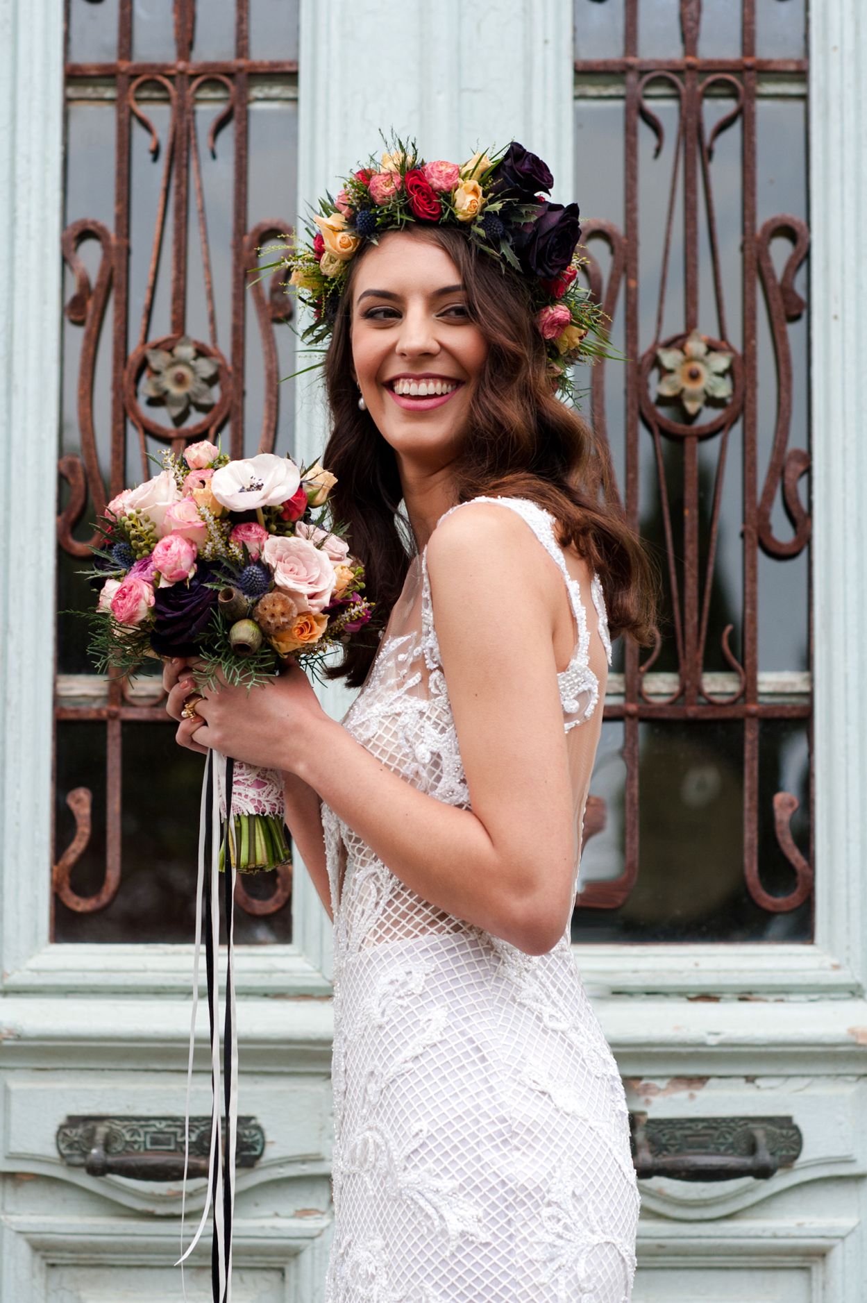 a smiling bride stands in front of a beautiful old door that is an interesting hue of light blue at Casita Miro