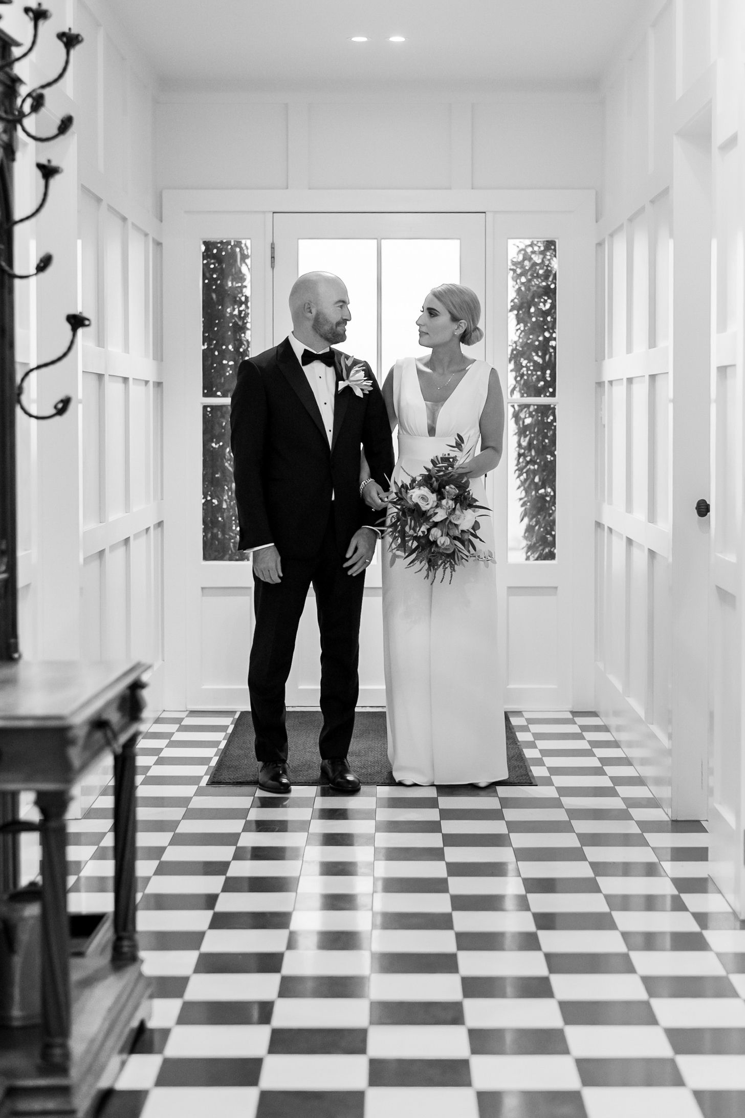 a black and white image of a wedding couple in a black and white chequered hallway