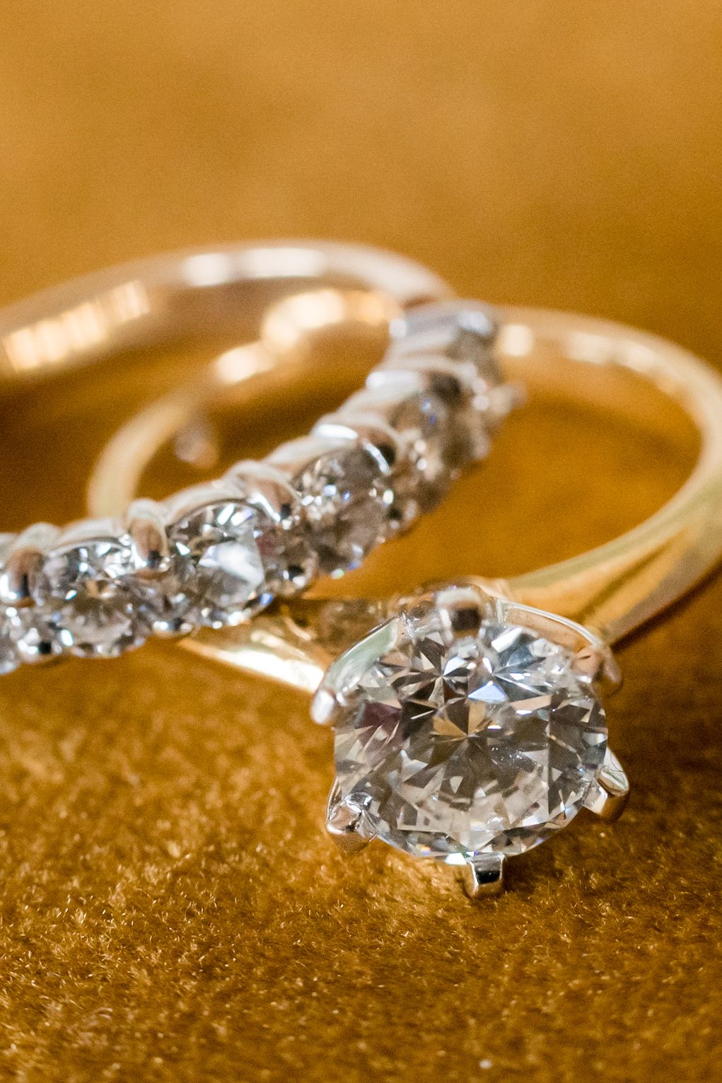 a very close up of the two rings on a deep yellow velvet background