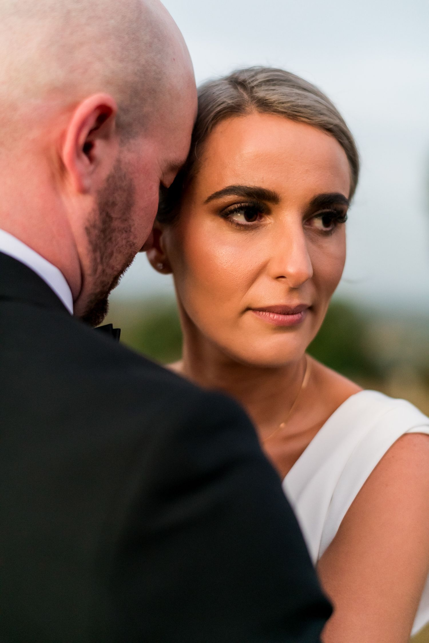 the bride looks to the side whilst in an embrace with the groom holding her