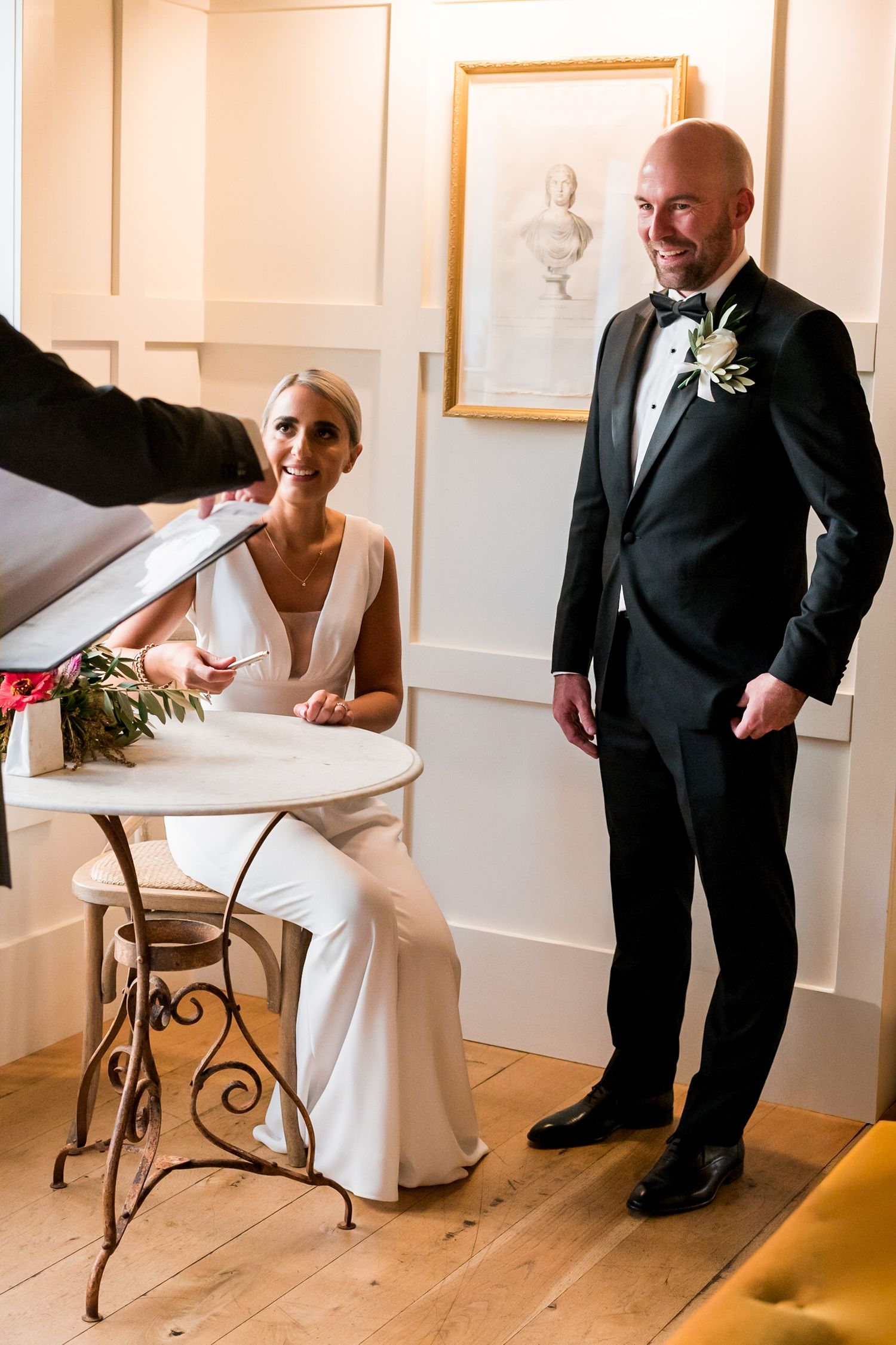 the signing of the wedding forms the couple are sitting and standing looking relaxed and happy