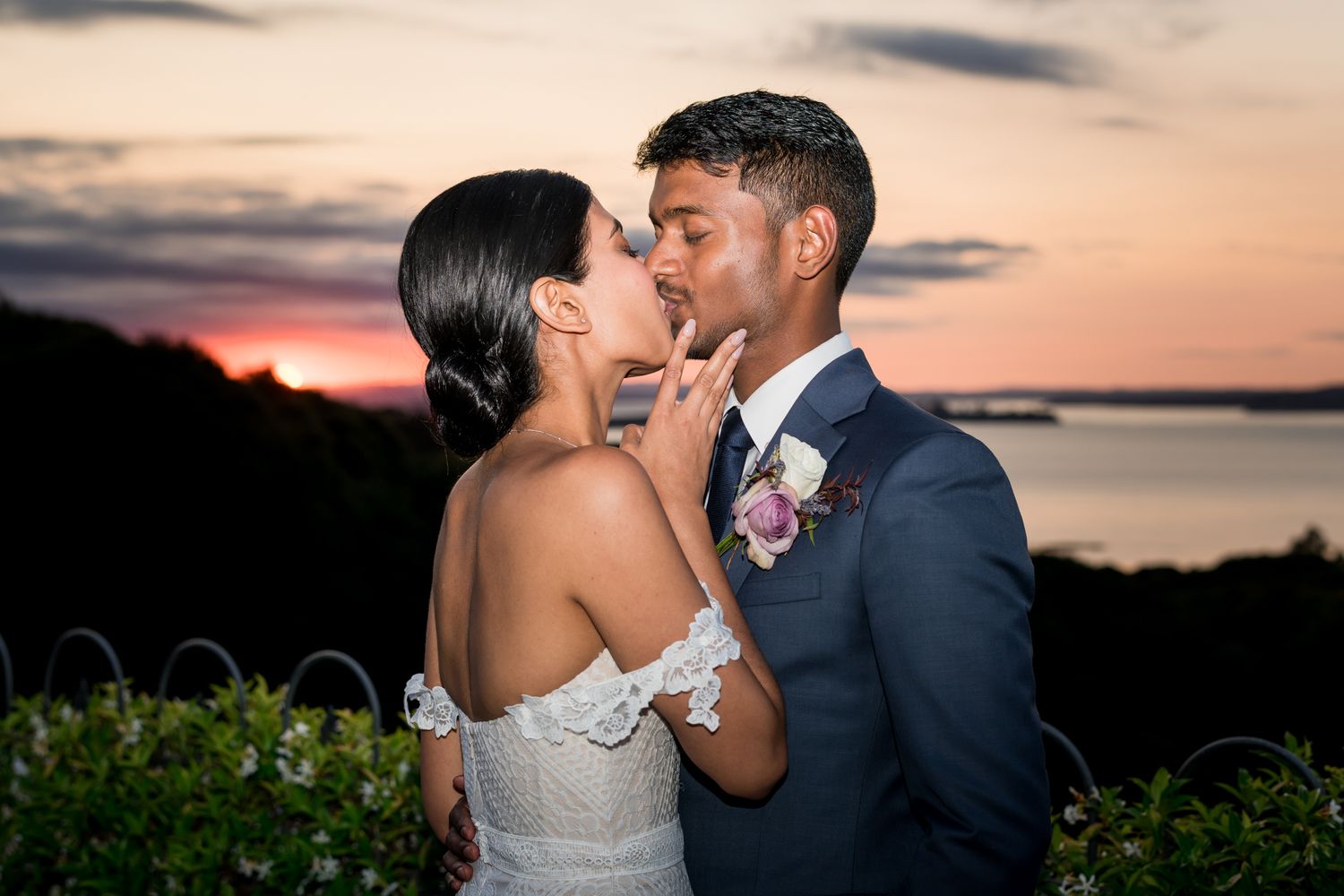 A dusk sunset photo of a bride kissing the groom
