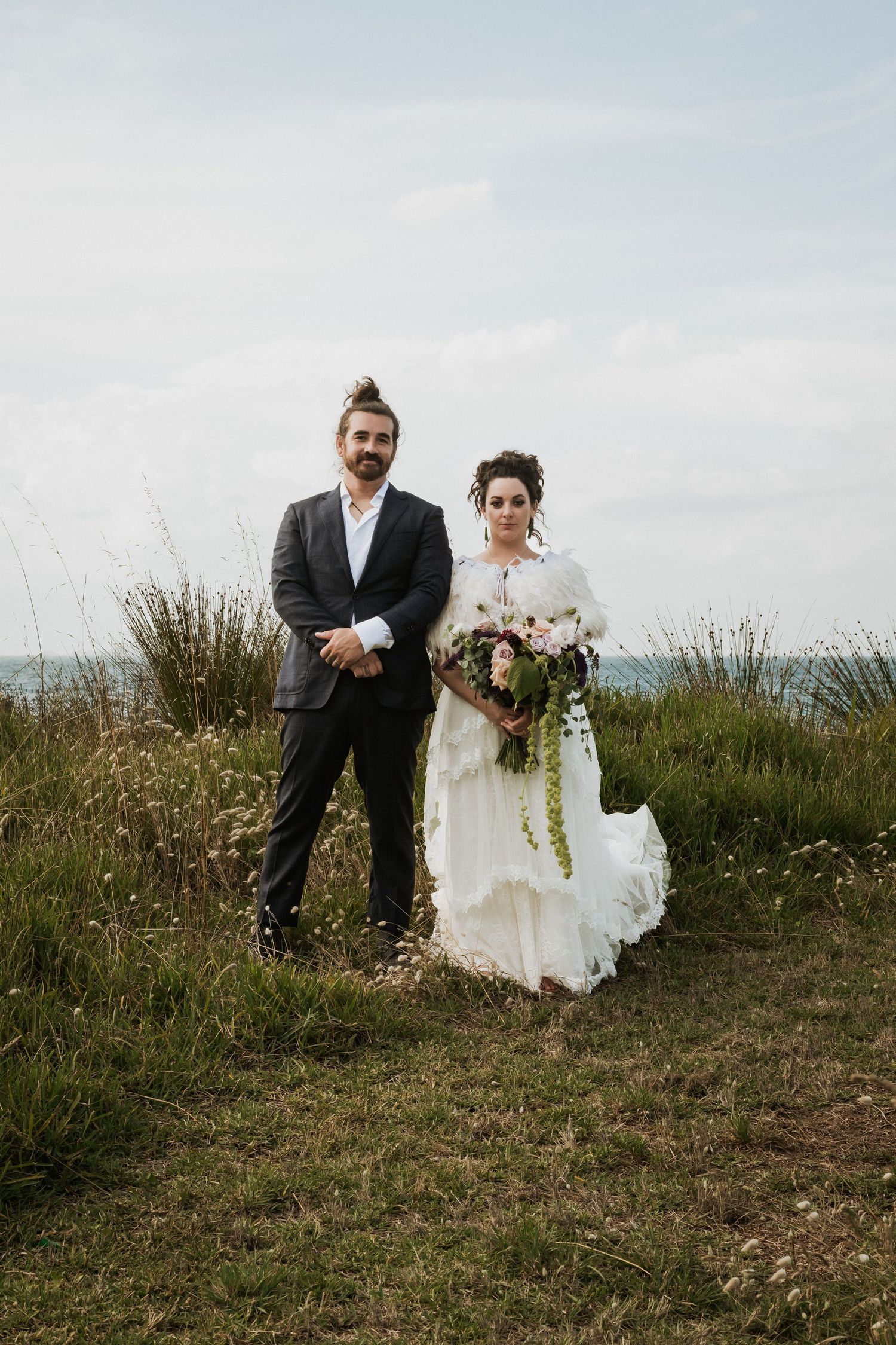 a wedding couple stand side by side looking straight towards the camera with a neutral look on their faces in a contemporary style portrait