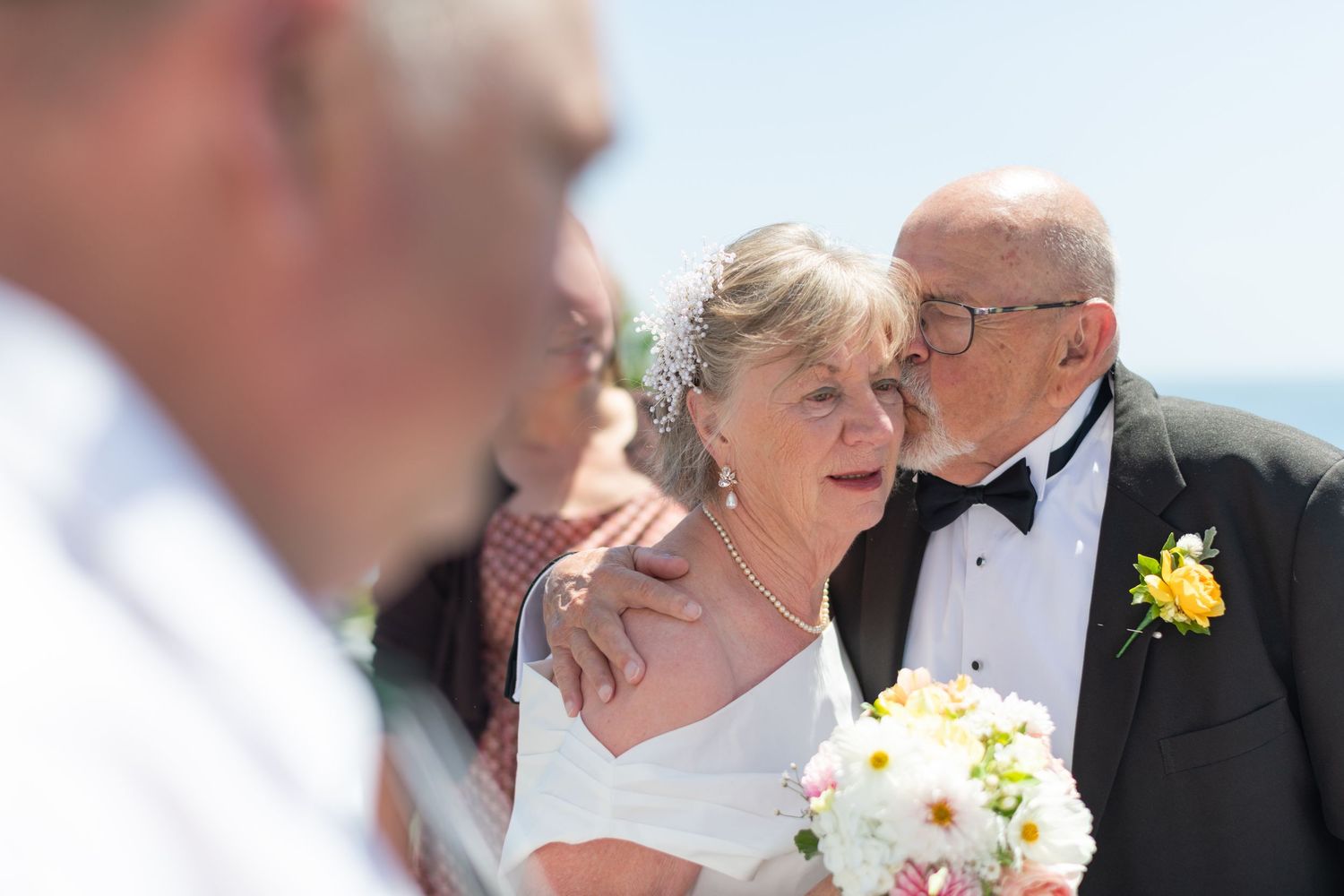 a bride and groom in their 80's have got married and he kisses her cheek affectionately
