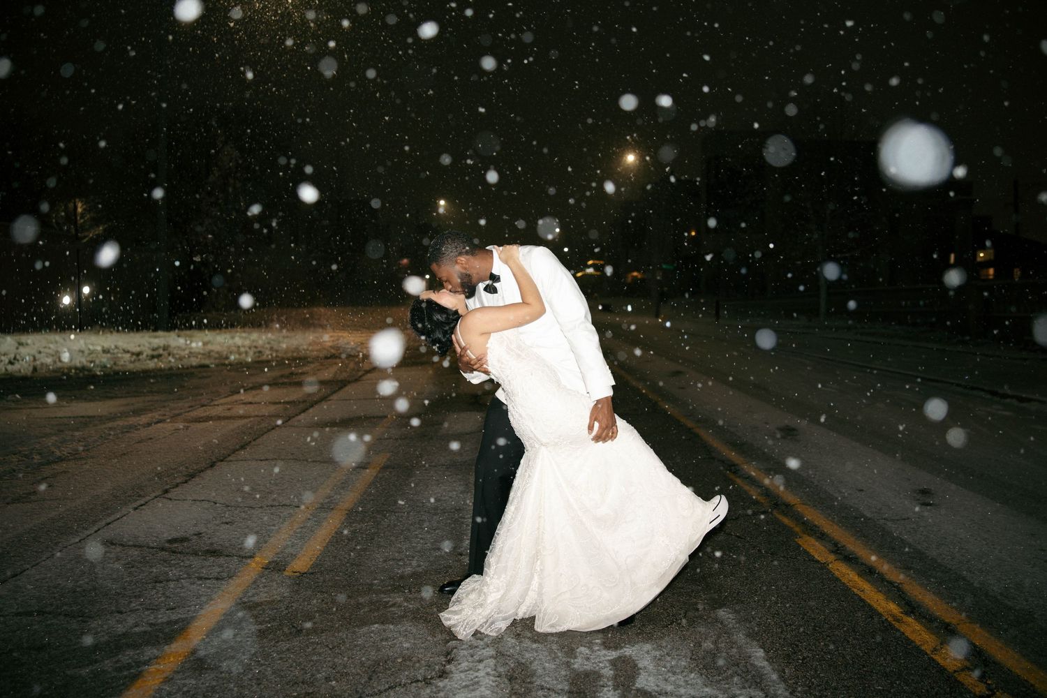 A couple dances in the snow during their winter wedding celebration.