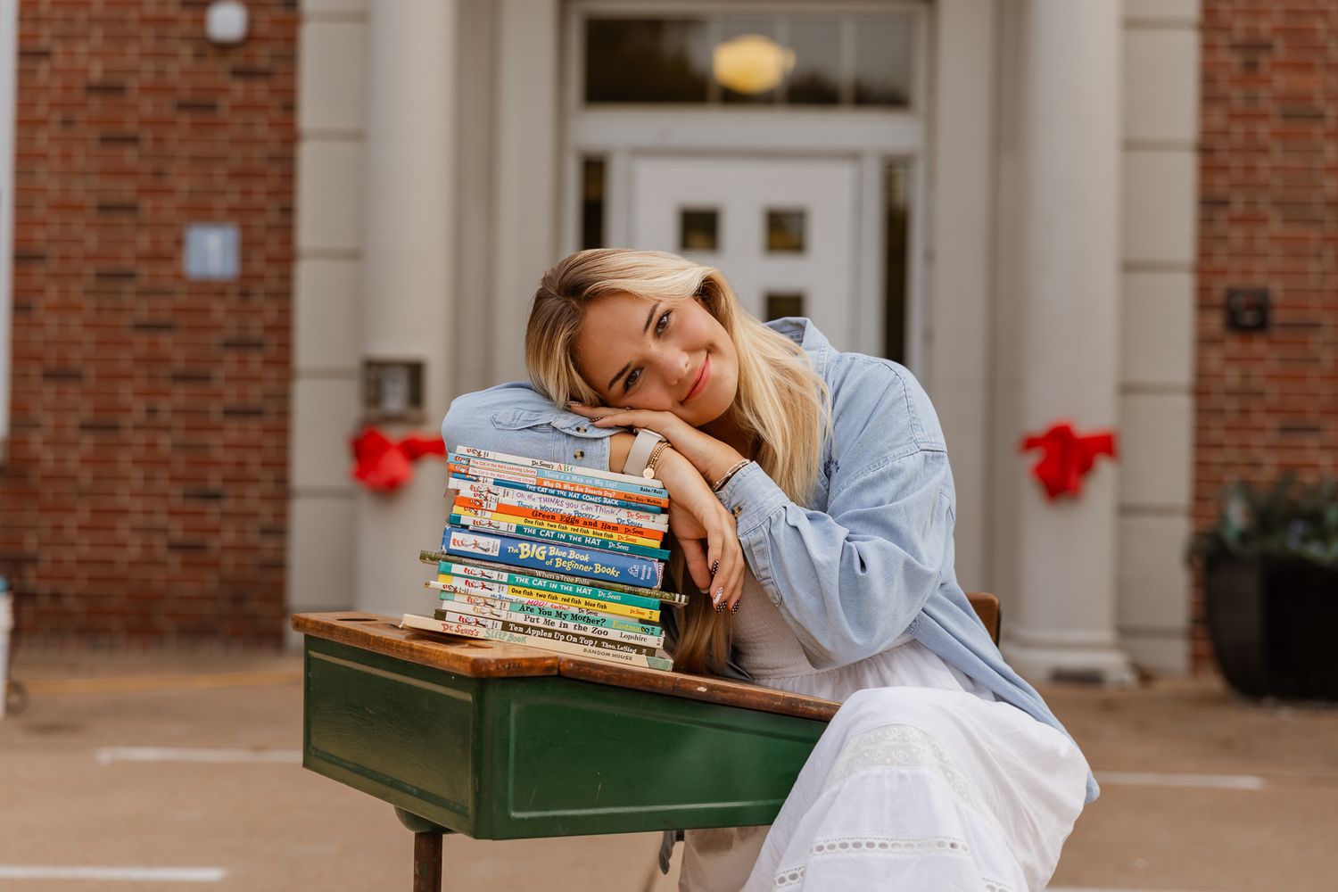 A white dress and blue shirt ensemble photographed against a classic brick school building.
