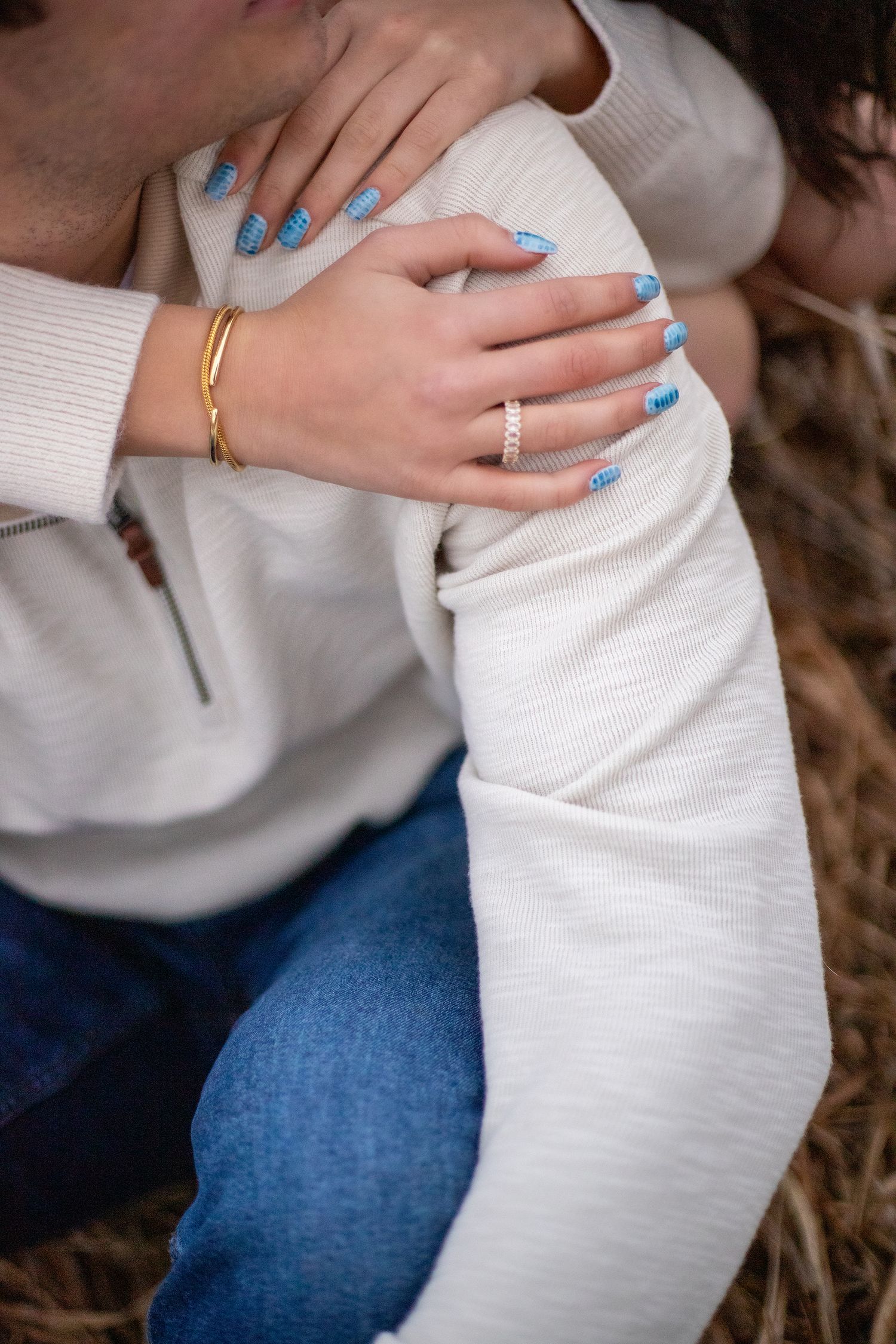 Close-up of hands with rings embracing in casual winter outfits.