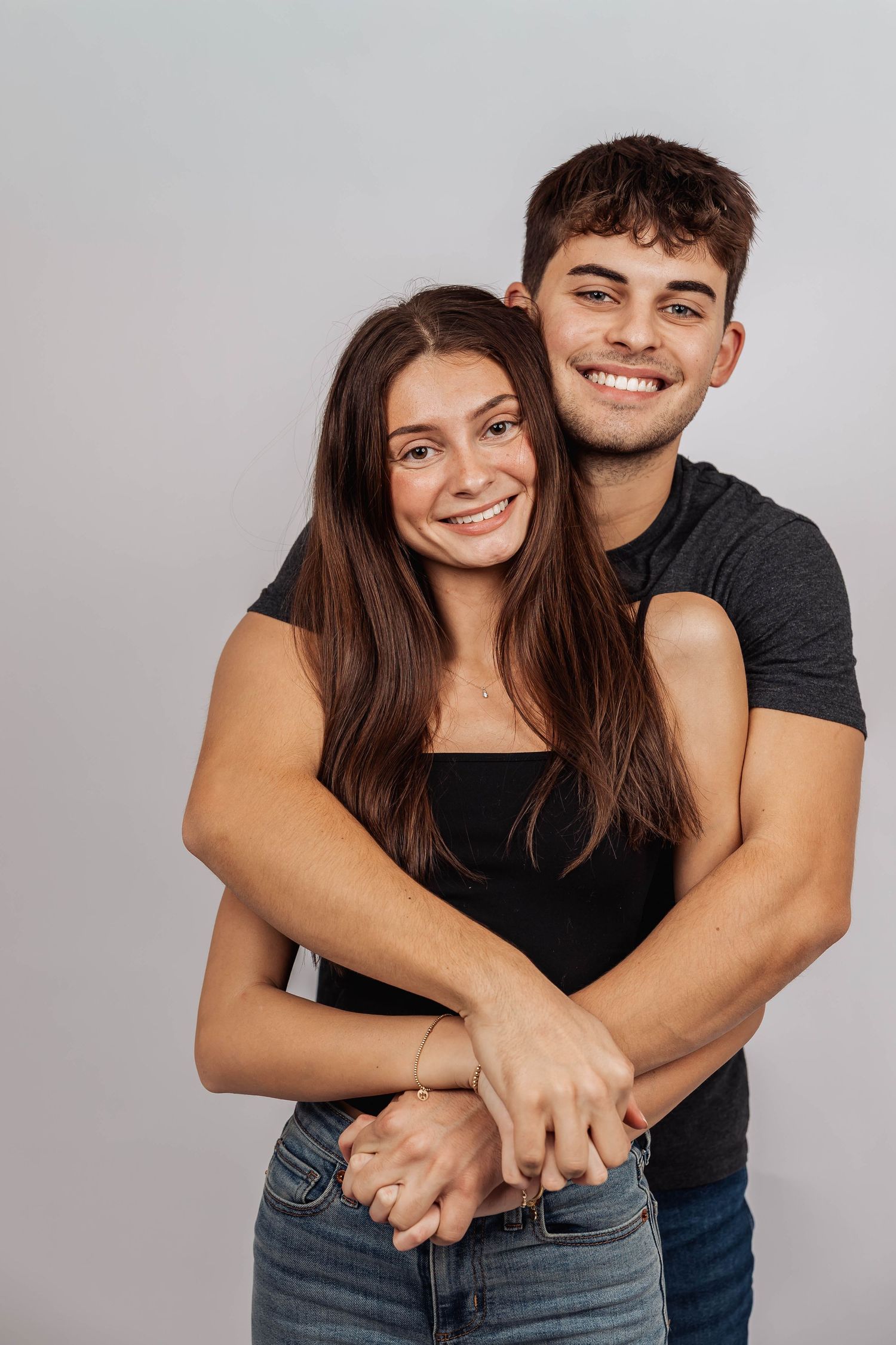 Happy couple sharing joyful embraces against white background.