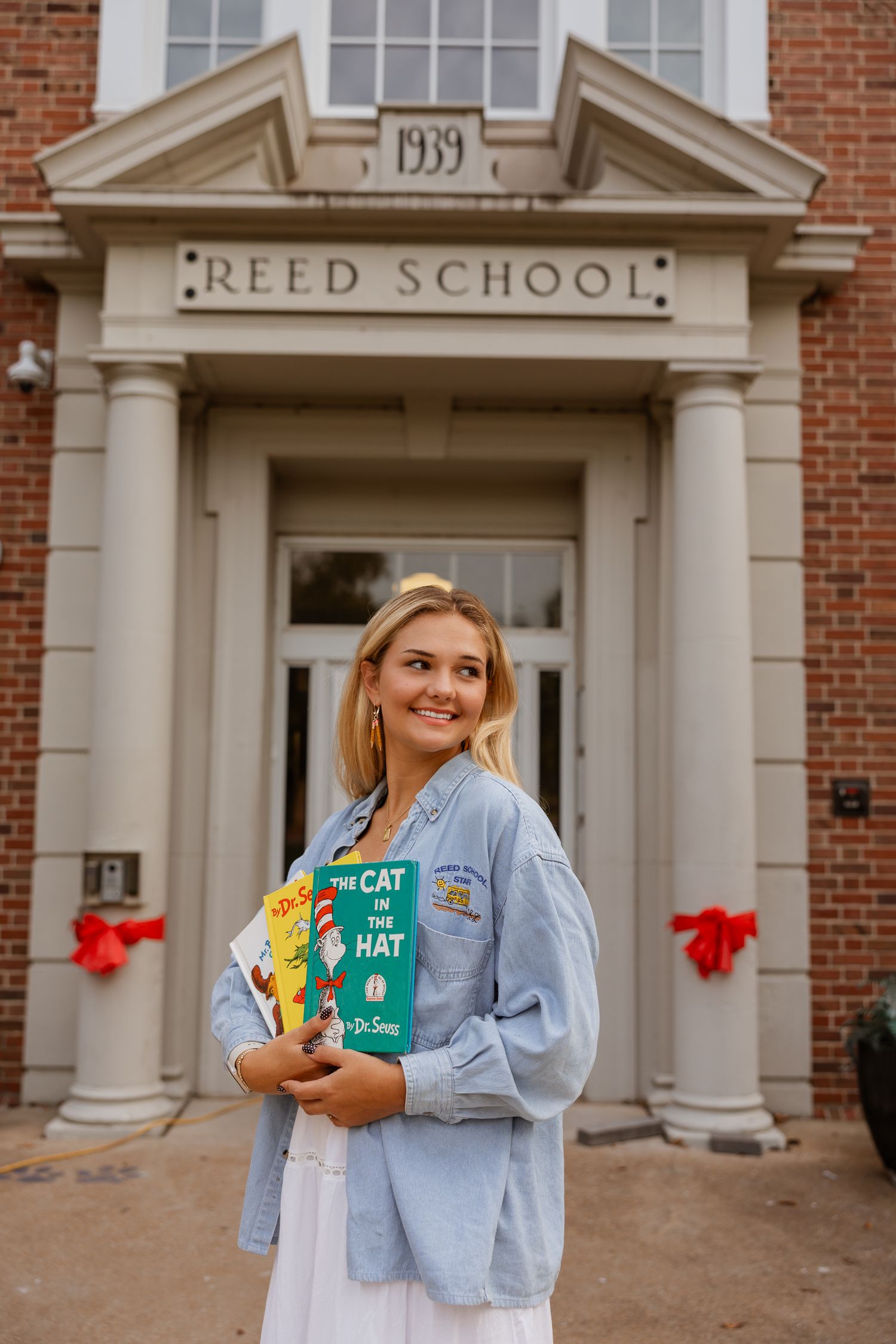 Someone displays classic children's books while posing at Reed School's historic entrance.