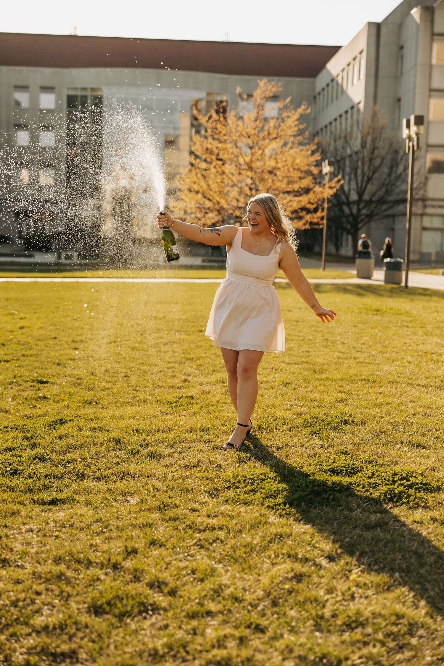 Person in white dress twirling in golden sunlight on grass field.