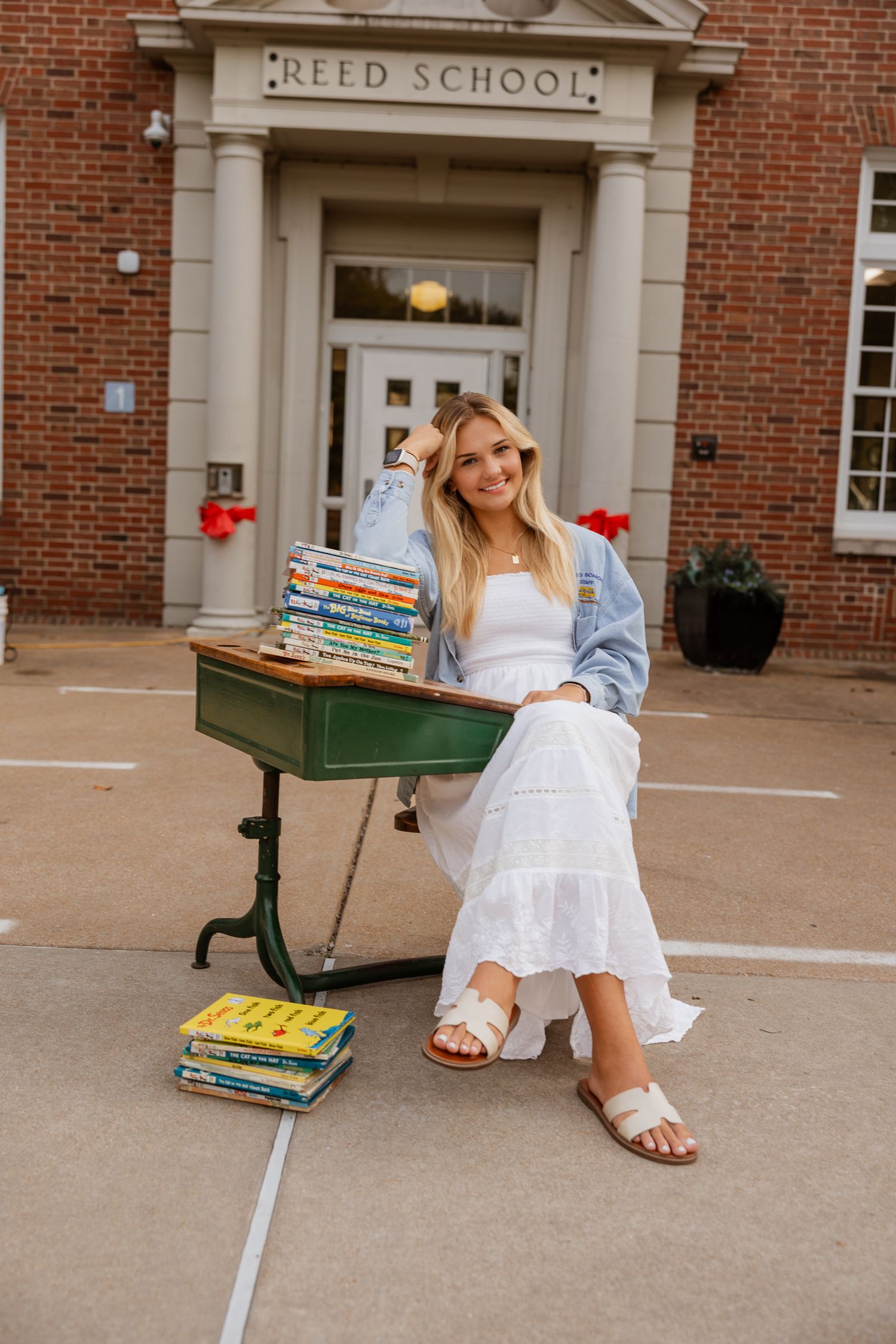 Someone sits casually on Reed School's steps with a stack of classic children's books.